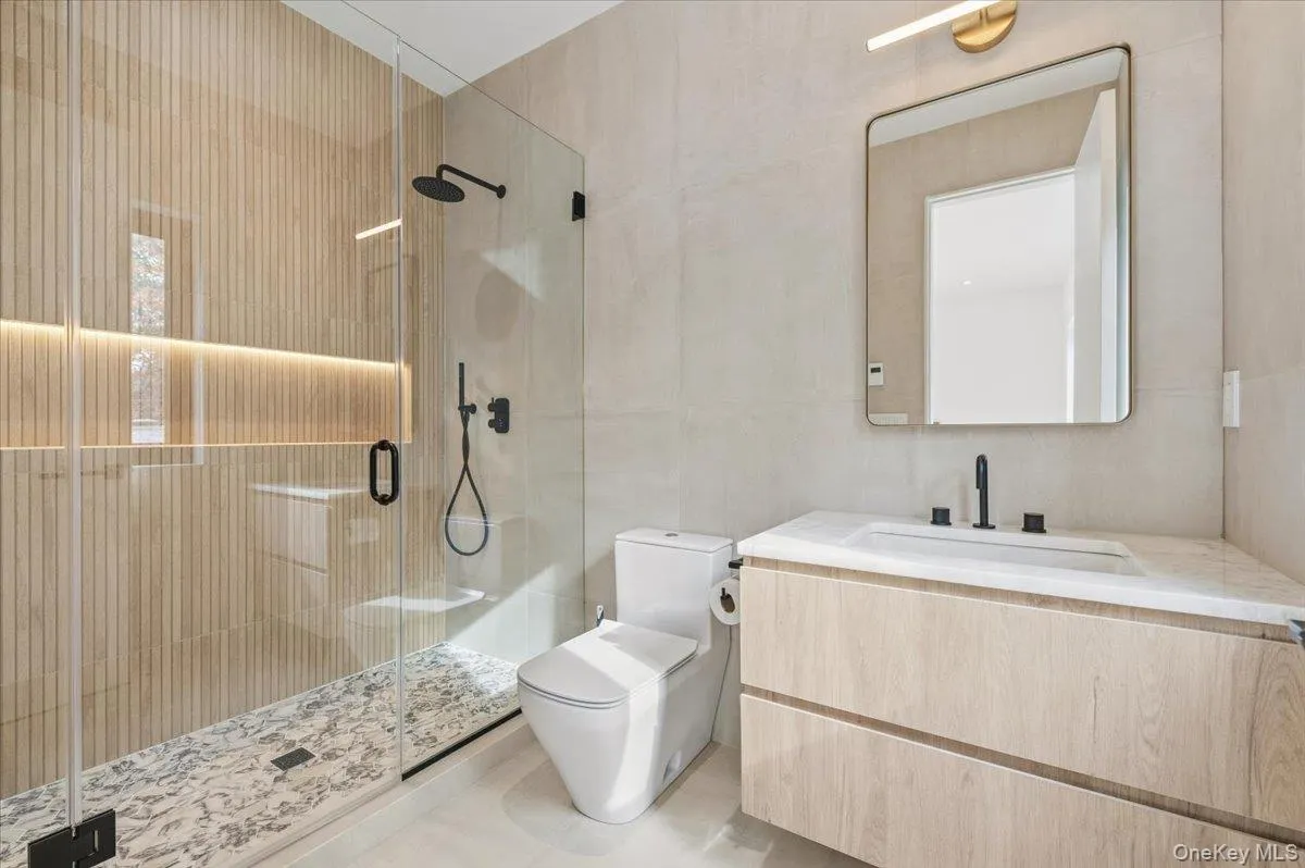 Full bathroom featuring tile walls, a stall shower, and vanity