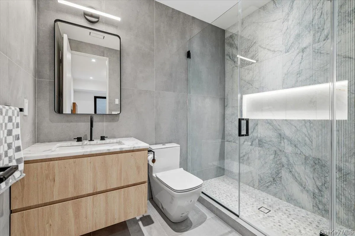 Bathroom with vanity, tile walls, and a marble finish shower