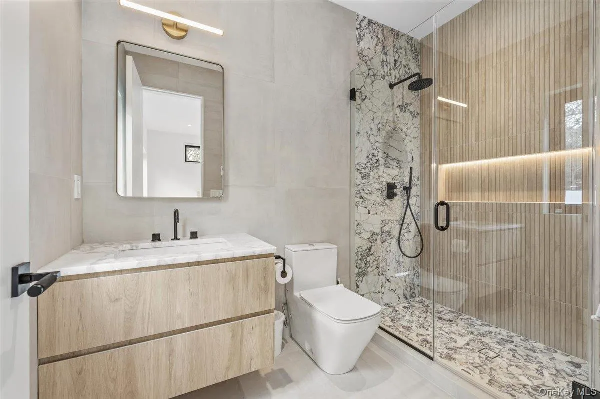 Bathroom featuring a stall shower, vanity, and tile walls
