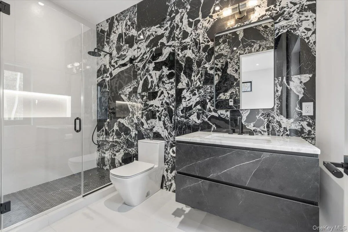 Full bath featuring tile walls, vanity, a shower stall, and tile patterned flooring