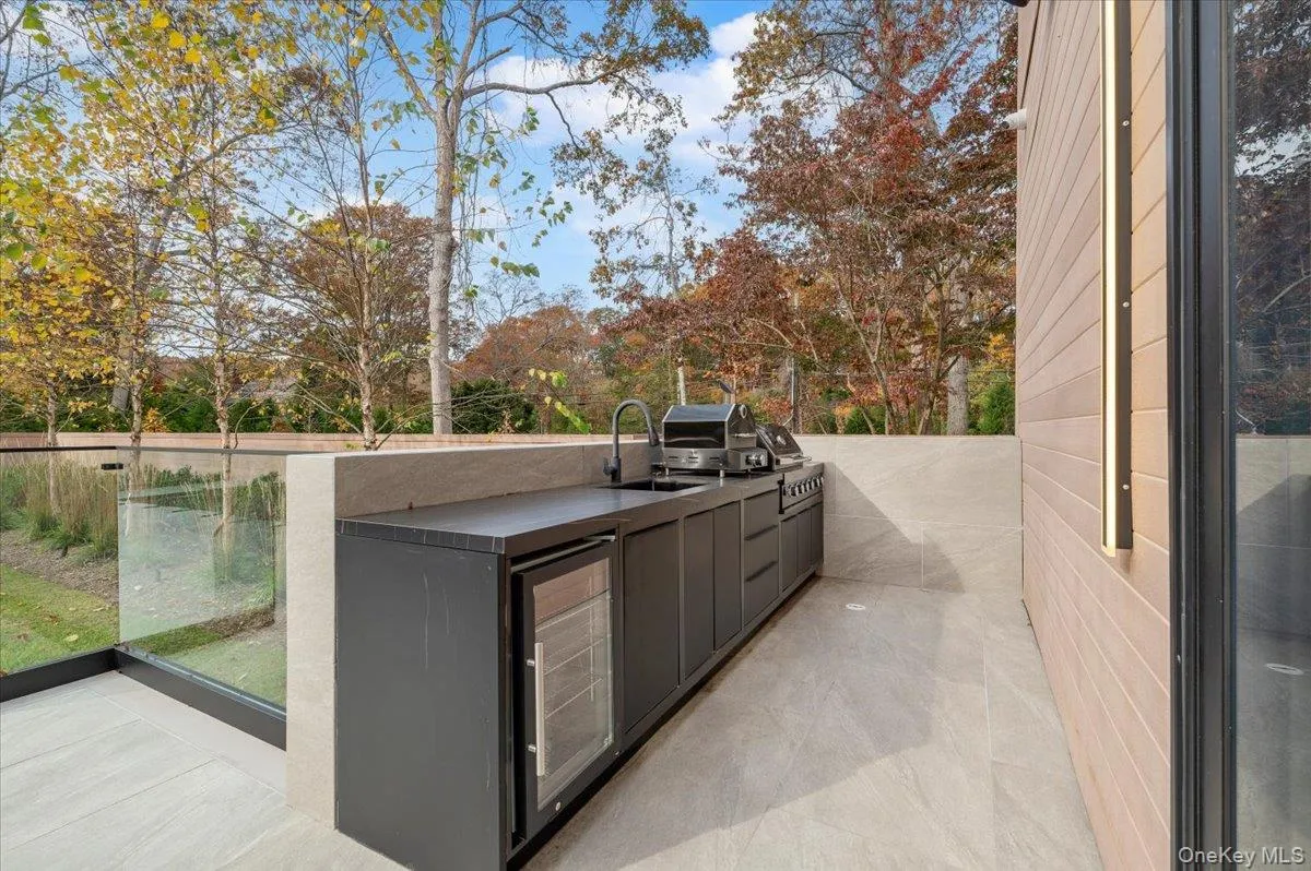 View of patio featuring area for grilling and view of scattered trees