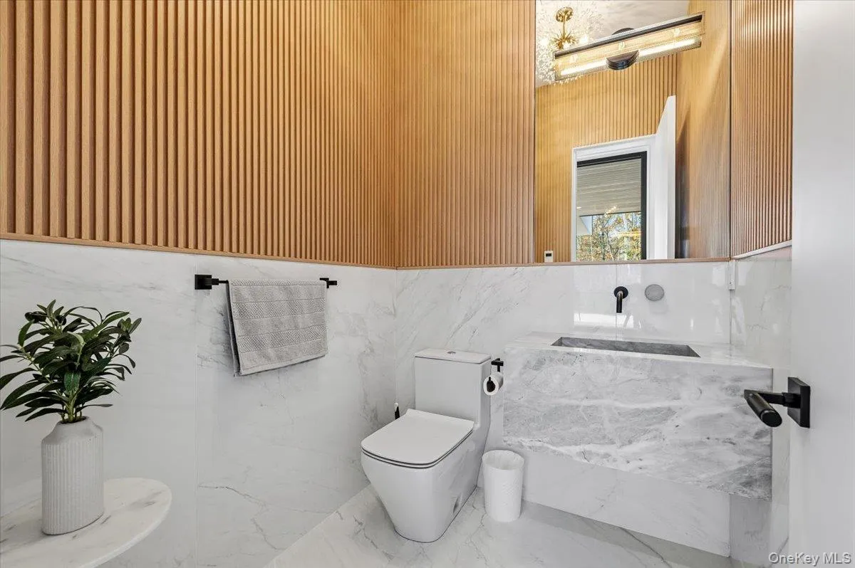Half bath with marble finish floors, vanity, and tile walls