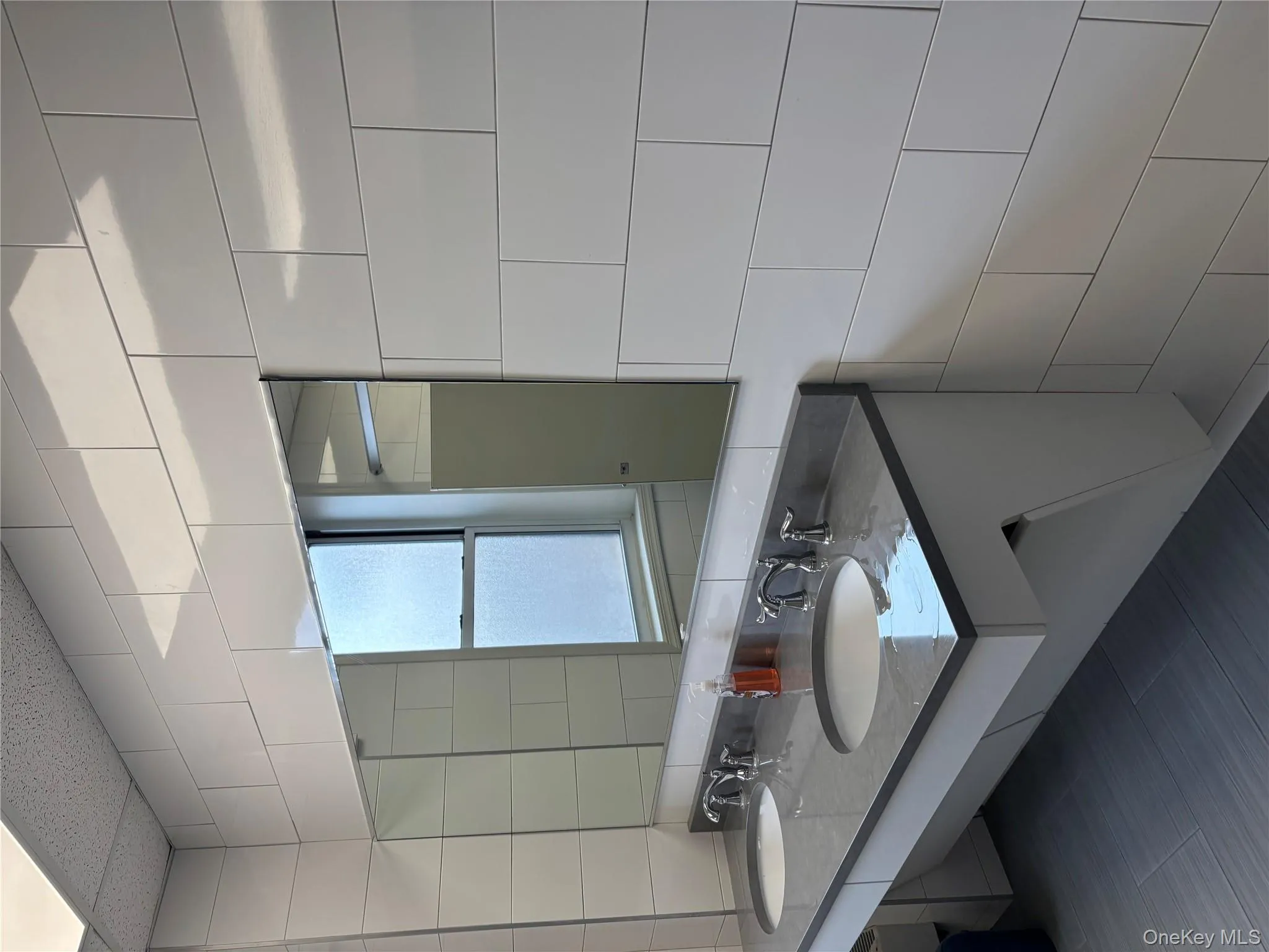 Bathroom featuring tile walls, double vanity, and tasteful backsplash Bathroom featuring tile walls, double vanity, and tasteful backsplash