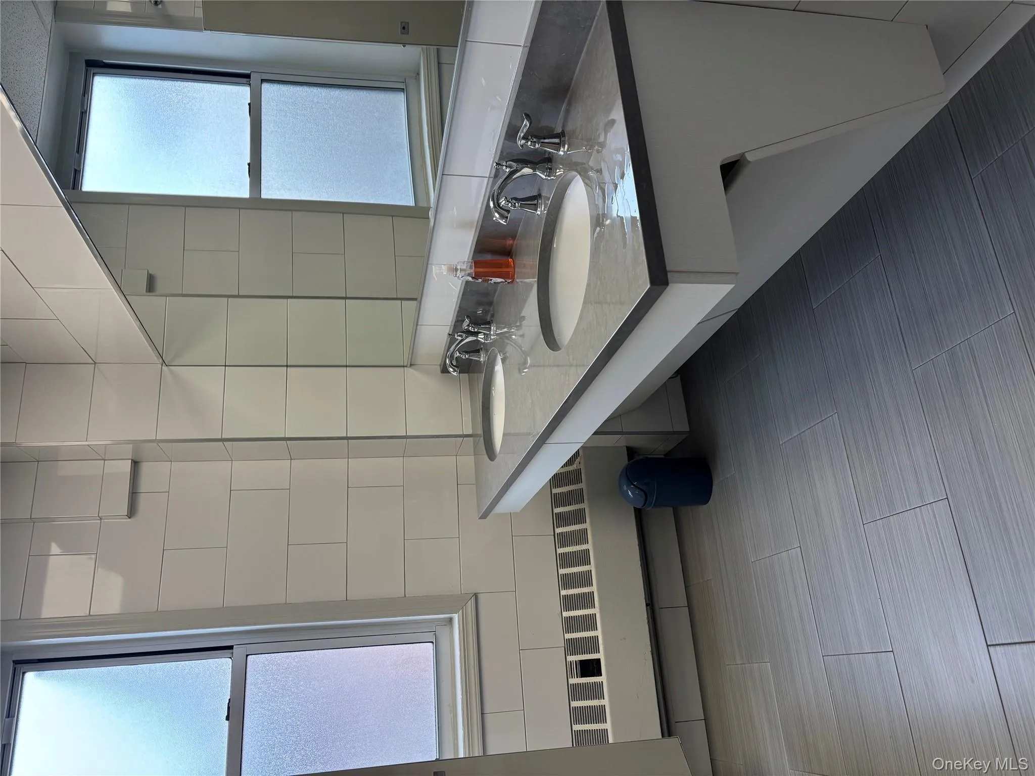 Full bath featuring tile walls, double vanity, and backsplash Full bath featuring tile walls, double vanity, and backsplash