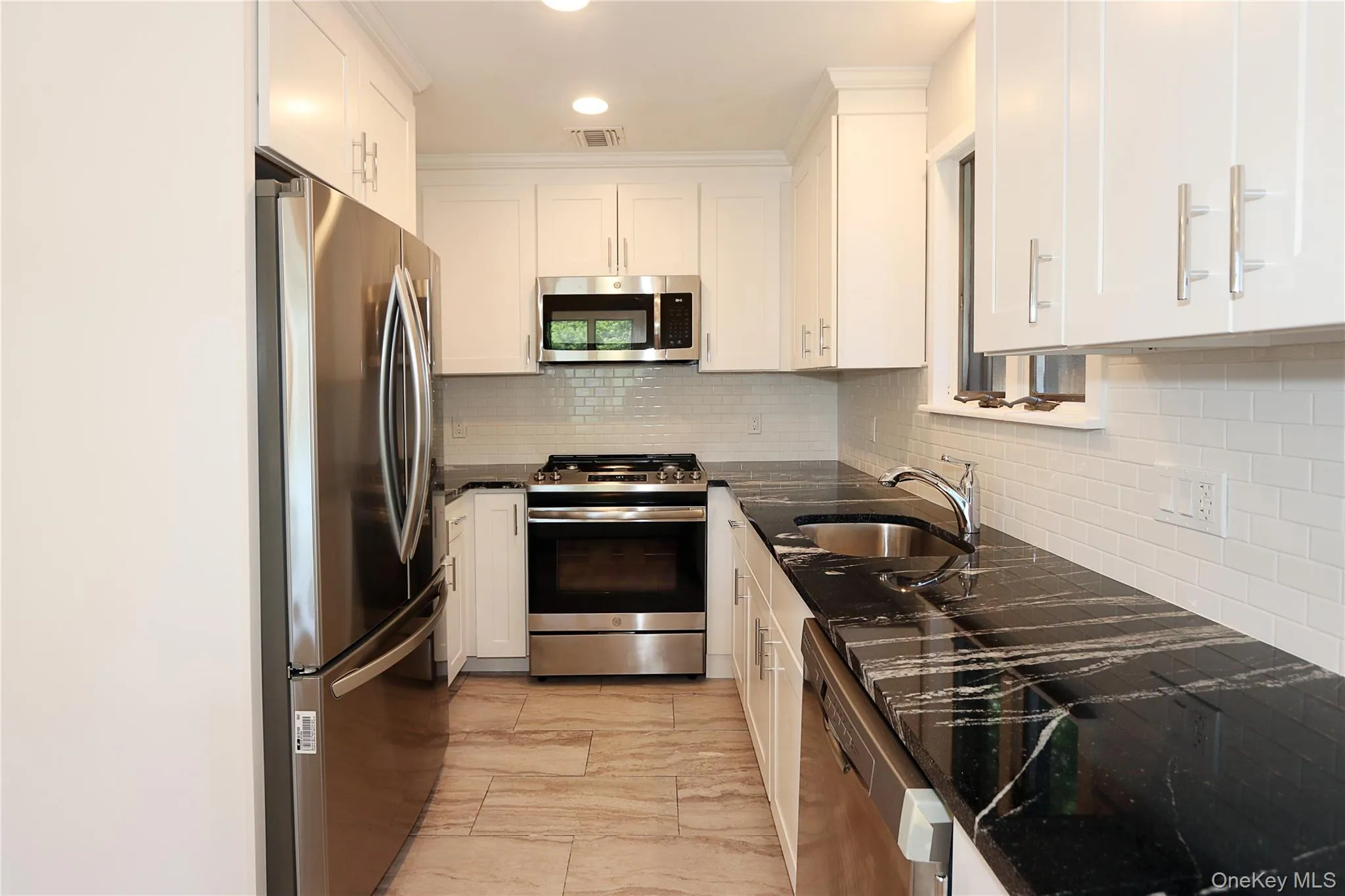 Kitchen with appliances with stainless steel finishes, decorative backsplash, dark stone countertops, white cabinets, and recessed lighting Kitchen with appliances with stainless steel finishes, decorative backsplash, dark stone countertops, white cabinets, and recessed lighting