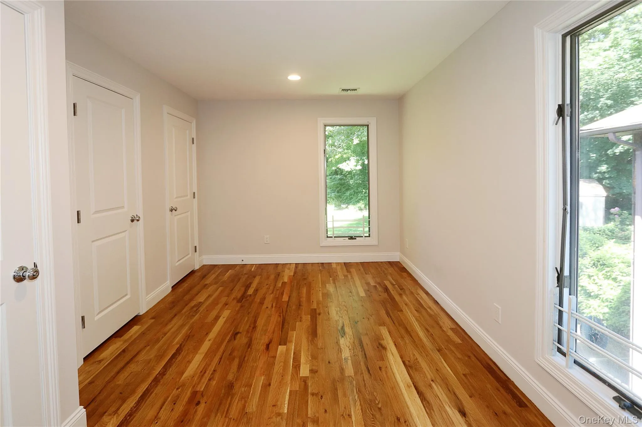 Unfurnished bedroom with light wood-style floors, recessed lighting, and multiple closets Unfurnished bedroom with light wood-style floors, recessed lighting, and multiple closets