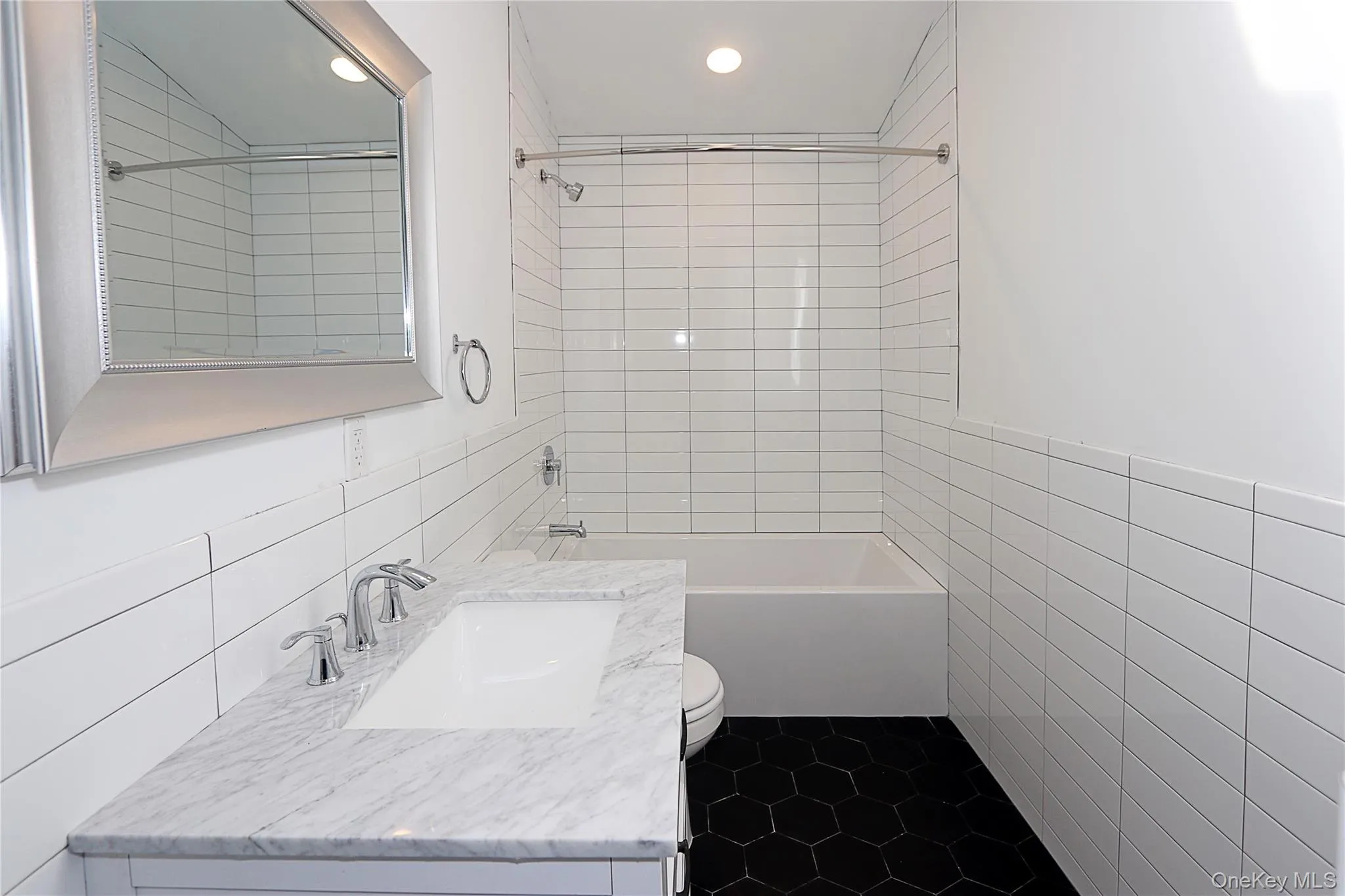 Full bath with tile walls, shower / washtub combination, vanity, recessed lighting, and dark tile patterned floors Full bath with tile walls, shower / washtub combination, vanity, recessed lighting, and dark tile patterned floors