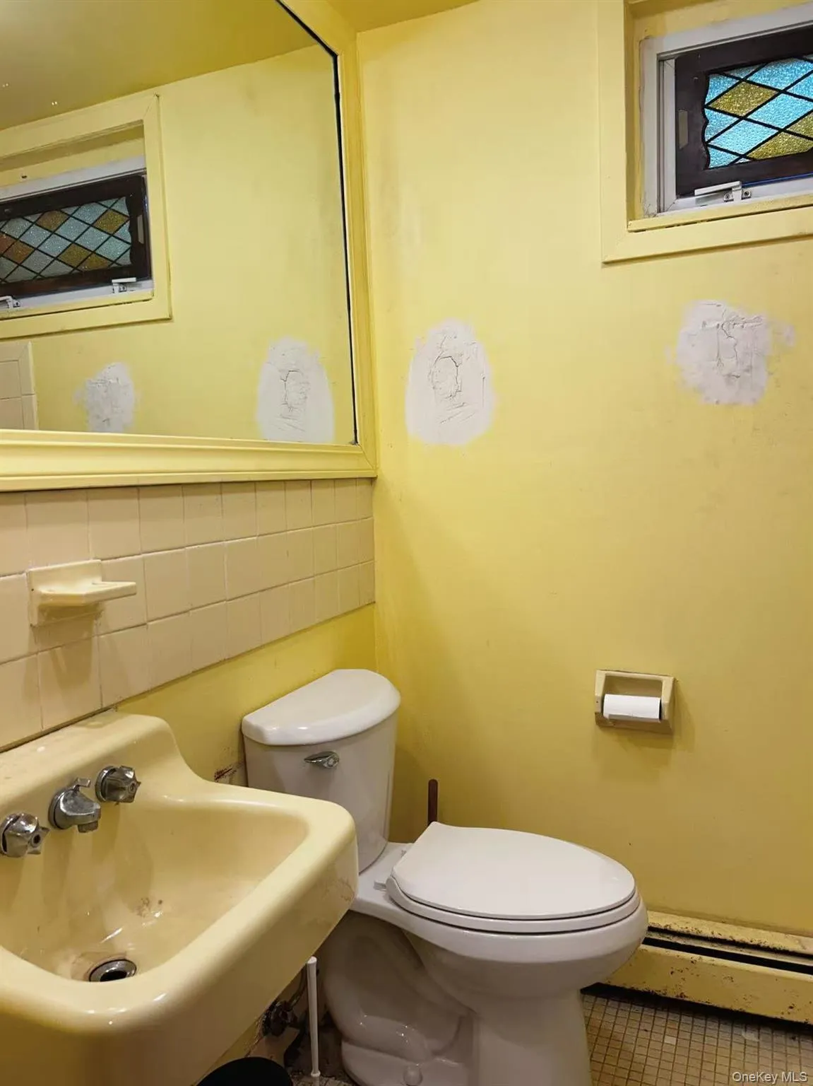 Half bathroom featuring tasteful backsplash, a baseboard heating unit, tile patterned floors, and tile walls Half bathroom featuring tasteful backsplash, a baseboard heating unit, tile patterned floors, and tile walls