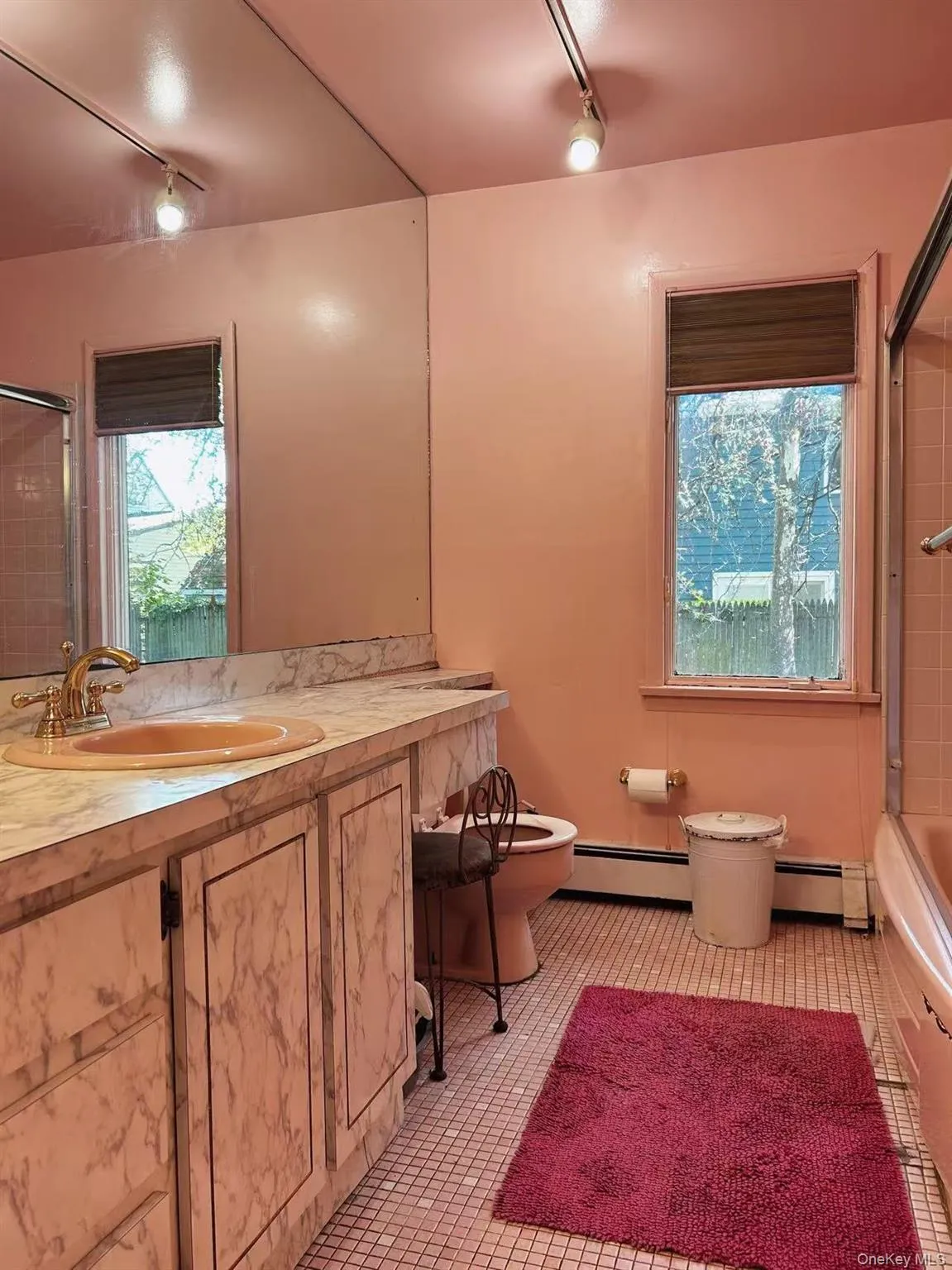 Full bathroom featuring track lighting, tiled shower / bath combo, vanity, and baseboard heating Full bathroom featuring track lighting, tiled shower / bath combo, vanity, and baseboard heating