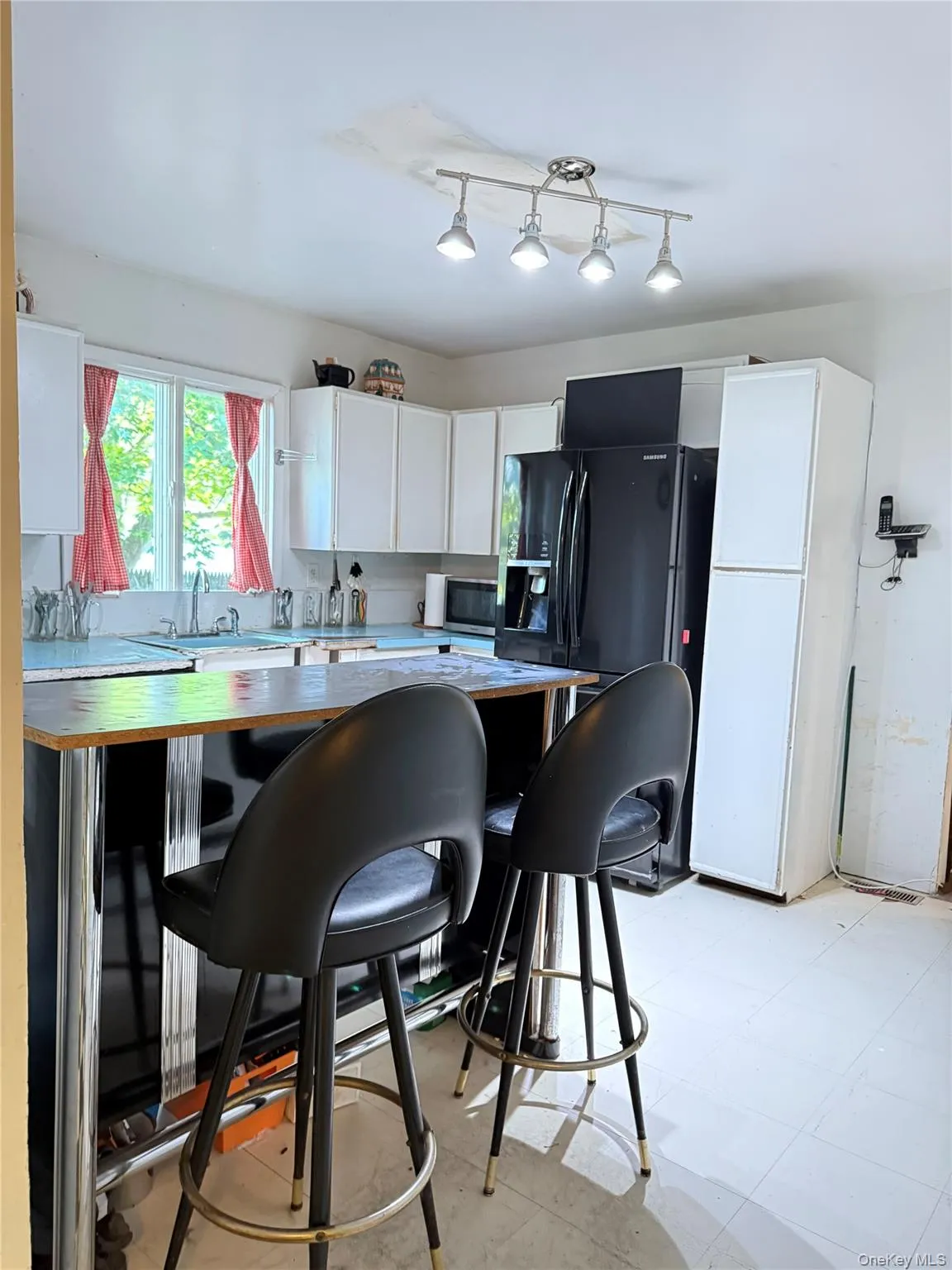 Kitchen featuring wood counters, white cabinets, black refrigerator with ice dispenser, and a breakfast bar Kitchen featuring wood counters, white cabinets, black refrigerator with ice dispenser, and a breakfast bar