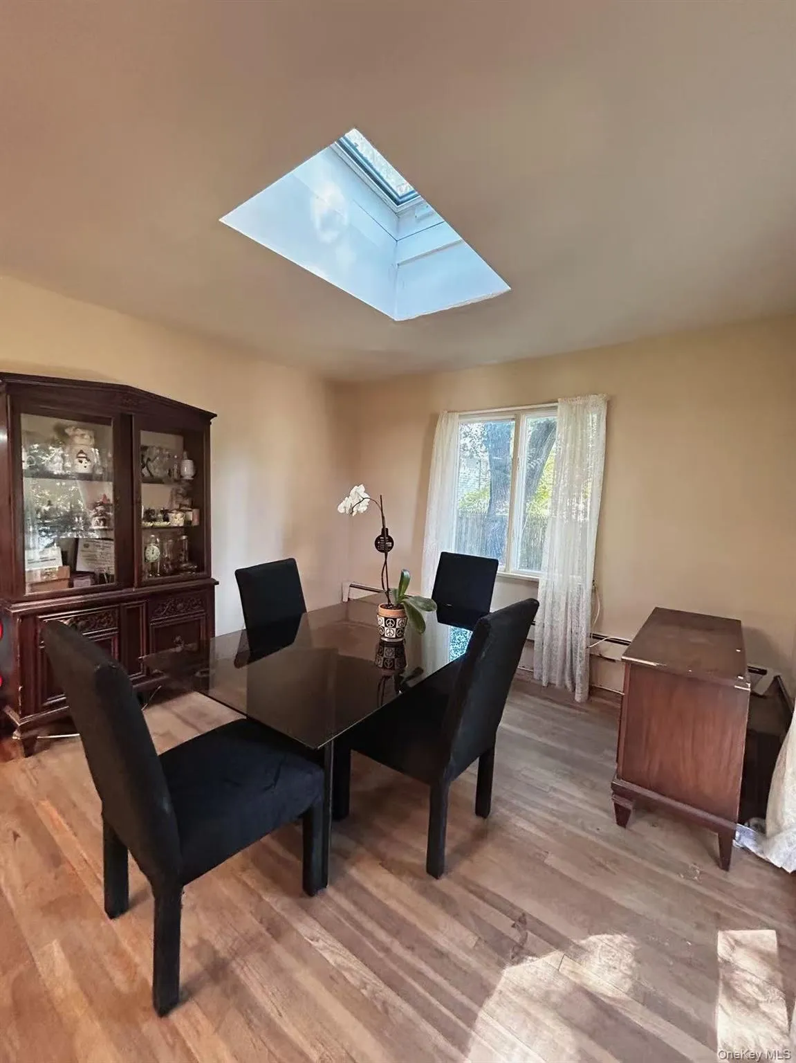 Dining room with a skylight and light wood-type flooring Dining room with a skylight and light wood-type flooring