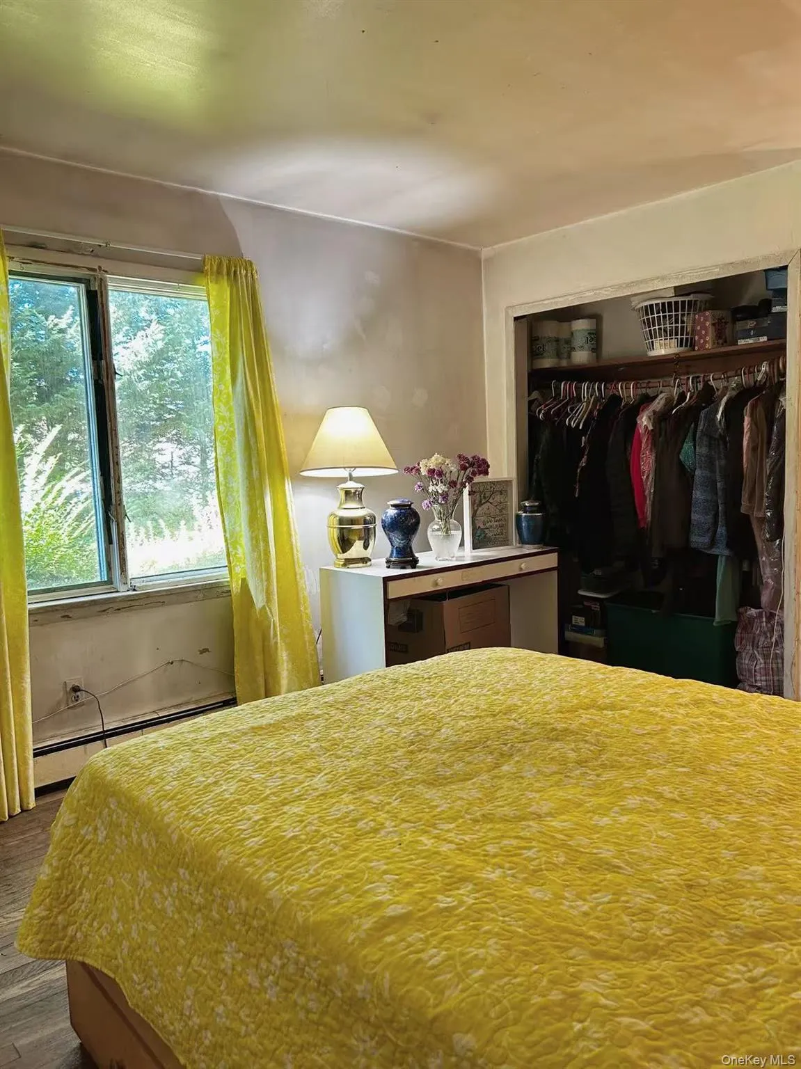 Bedroom with baseboard heating, a closet, and wood finished floors Bedroom with baseboard heating, a closet, and wood finished floors