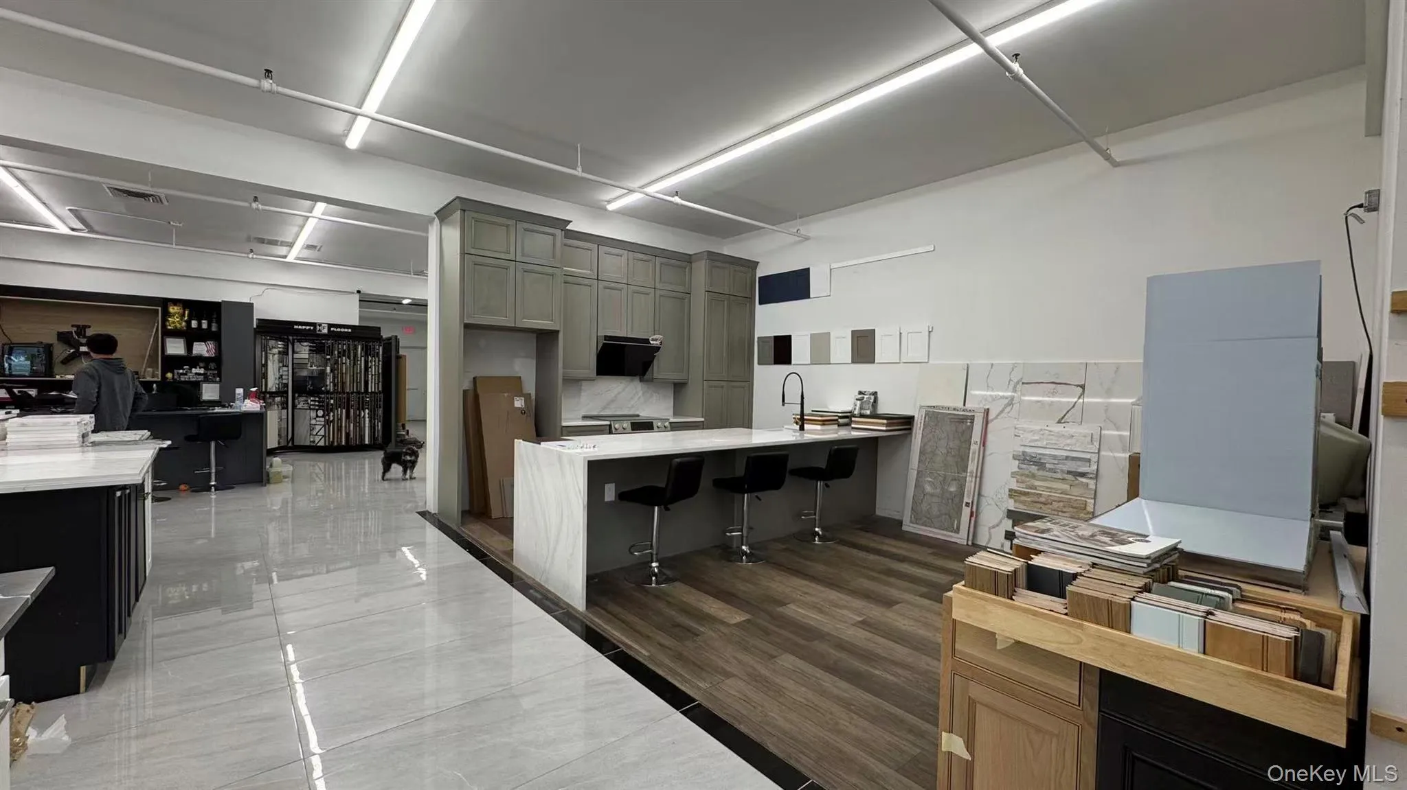 Kitchen with a kitchen breakfast bar, a peninsula, gray cabinets, light stone countertops, and under cabinet range hood Kitchen with a kitchen breakfast bar, a peninsula, gray cabinets, light stone countertops, and under cabinet range hood