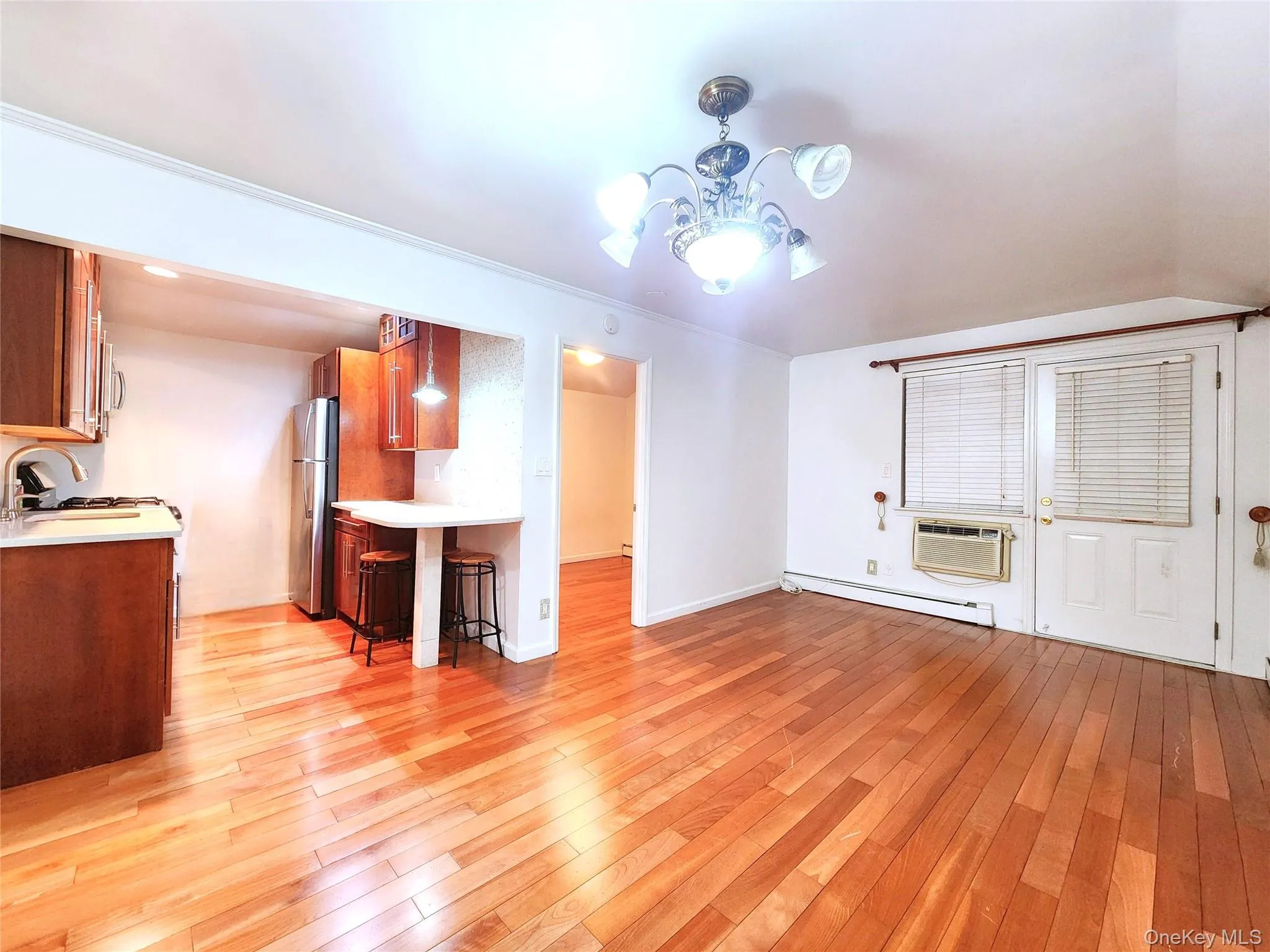Unfurnished living room with light wood-style floors, a chandelier, and a baseboard heating unit Unfurnished living room with light wood-style floors, a chandelier, and a baseboard heating unit