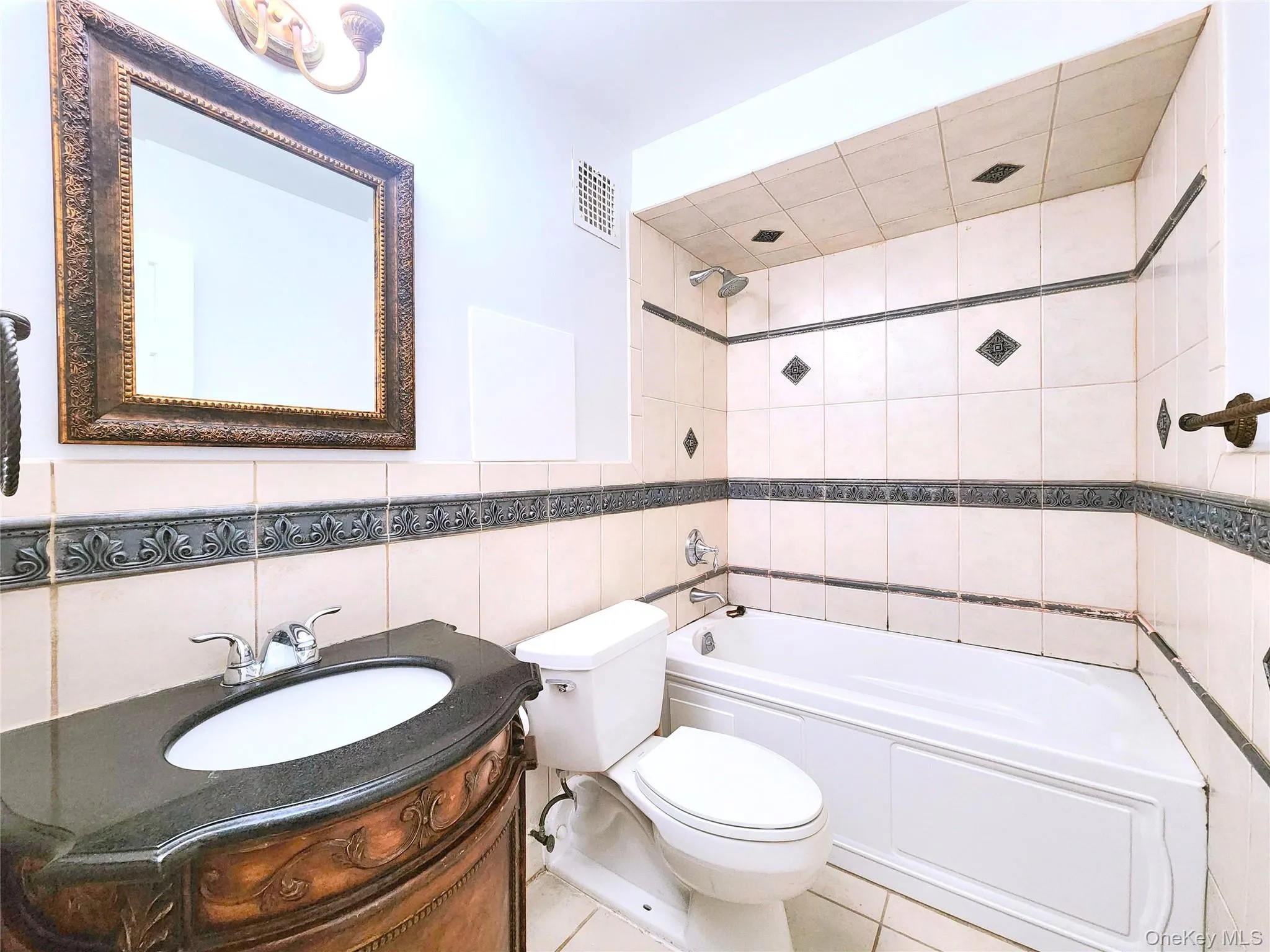 Bathroom with tile walls, shower / tub combination, vanity, and tile patterned flooring Bathroom with tile walls, shower / tub combination, vanity, and tile patterned flooring