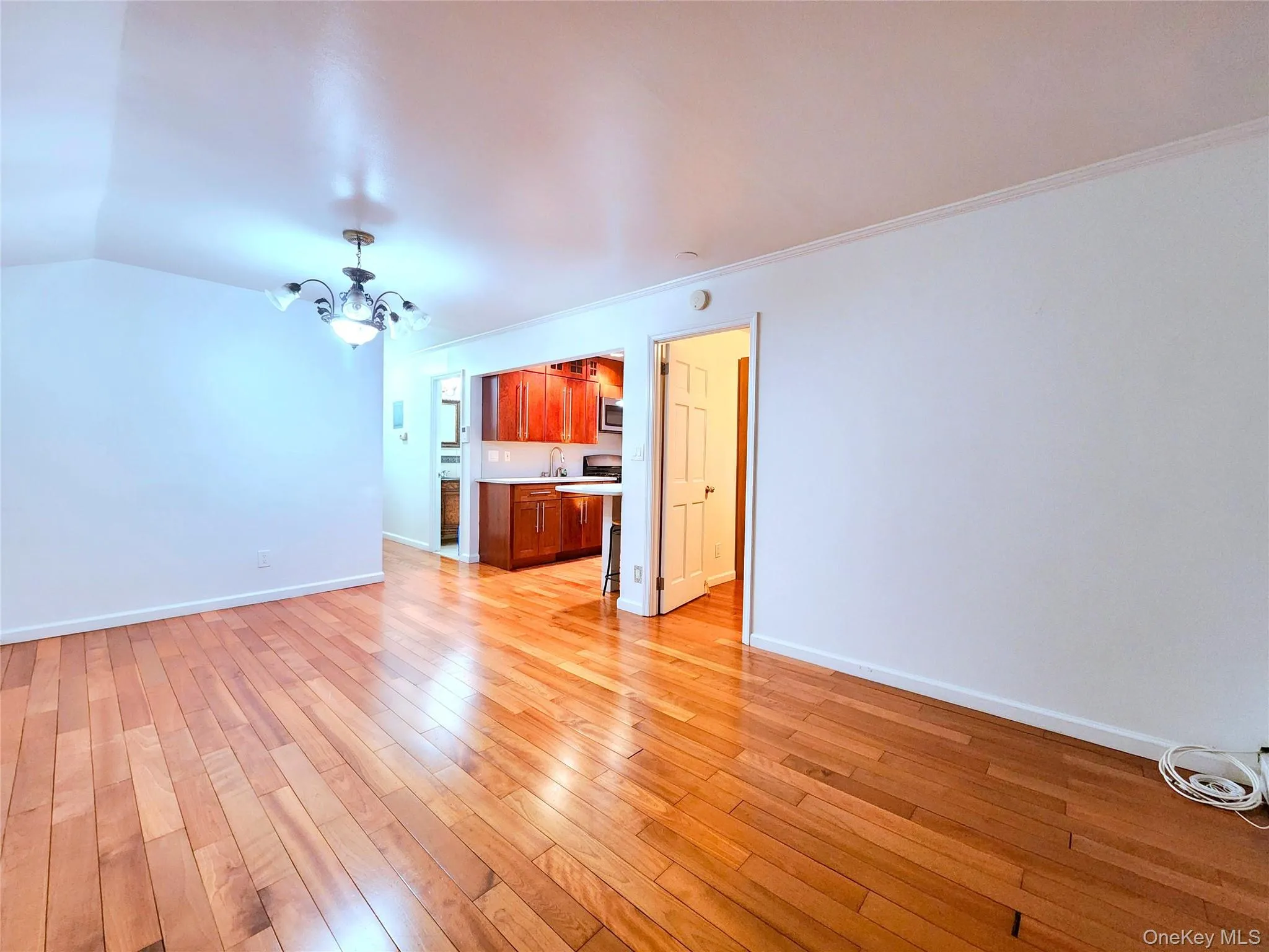 Unfurnished living room with a chandelier, light wood-style flooring, and crown molding Unfurnished living room with a chandelier, light wood-style flooring, and crown molding