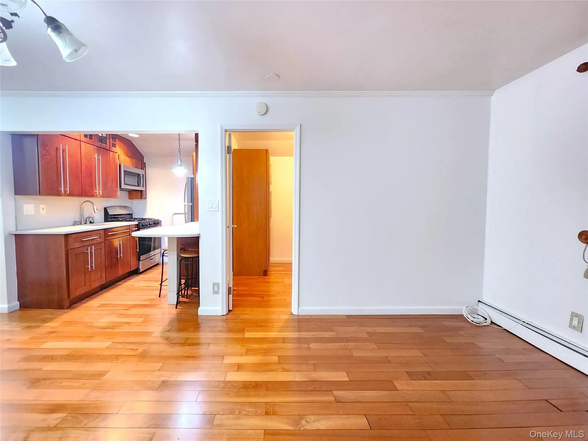Kitchen featuring a kitchen bar, light countertops, stainless steel appliances, light wood finished floors, and decorative light fixtures Kitchen featuring a kitchen bar, light countertops, stainless steel appliances, light wood finished floors, and decorative light fixtures