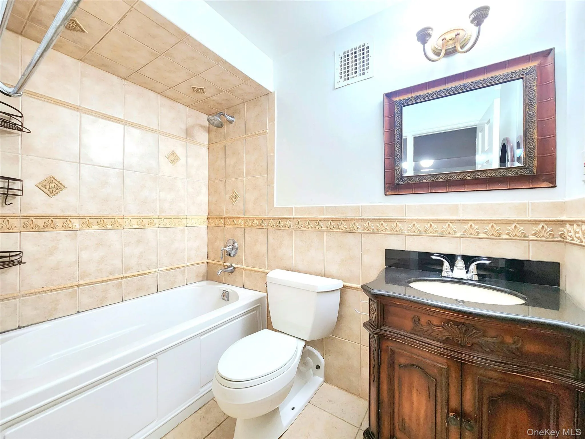 Full bathroom with tile walls, vanity, shower / washtub combination, and tile patterned floors Full bathroom with tile walls, vanity, shower / washtub combination, and tile patterned floors