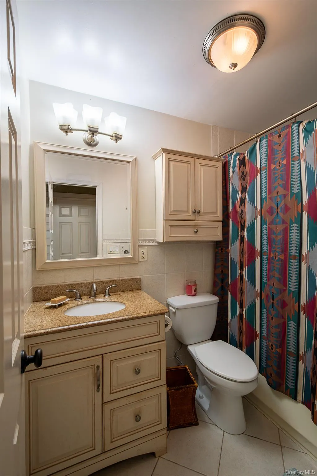 Bathroom featuring vanity, light tile patterned floors, shower / bath combination with curtain, and tile walls Bathroom featuring vanity, light tile patterned floors, shower / bath combination with curtain, and tile walls