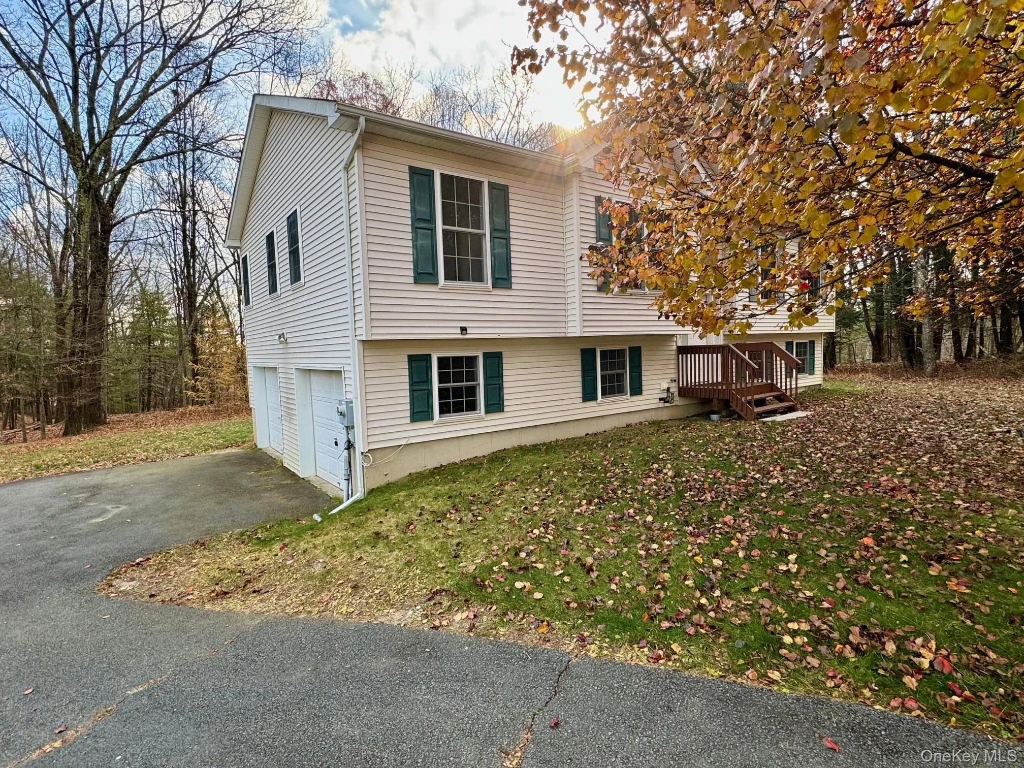 View of side of home featuring driveway, a garage, a lawn, and a wooden deck View of side of home featuring driveway, a garage, a lawn, and a wooden deck
