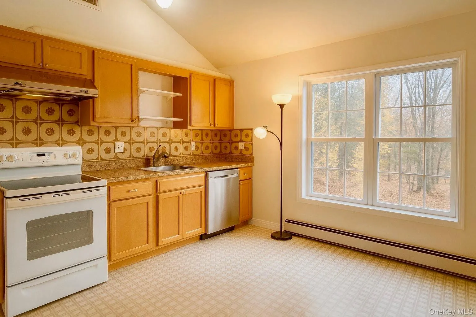 Kitchen featuring white range with electric cooktop, vaulted ceiling, a baseboard heating unit, light floors, and under cabinet range hood Kitchen featuring white range with electric cooktop, vaulted ceiling, a baseboard heating unit, light floors, and under cabinet range hood