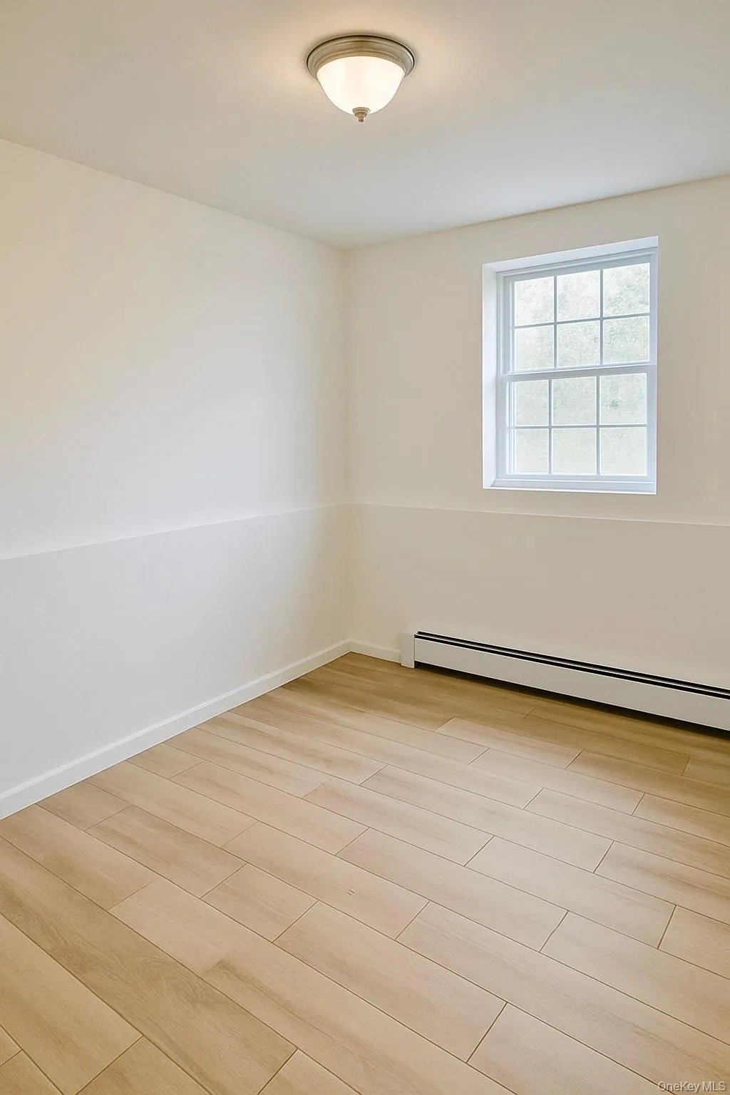 Empty room with baseboard heating and light wood-style floors Empty room with baseboard heating and light wood-style floors