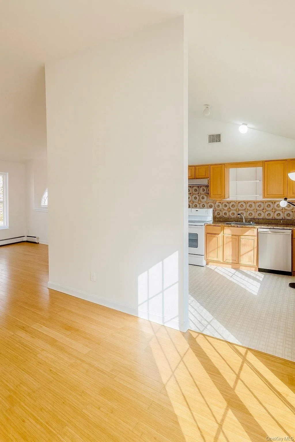 Kitchen with light wood-style flooring, lofted ceiling, white electric range, dishwasher, and tasteful backsplash Kitchen with light wood-style flooring, lofted ceiling, white electric range, dishwasher, and tasteful backsplash