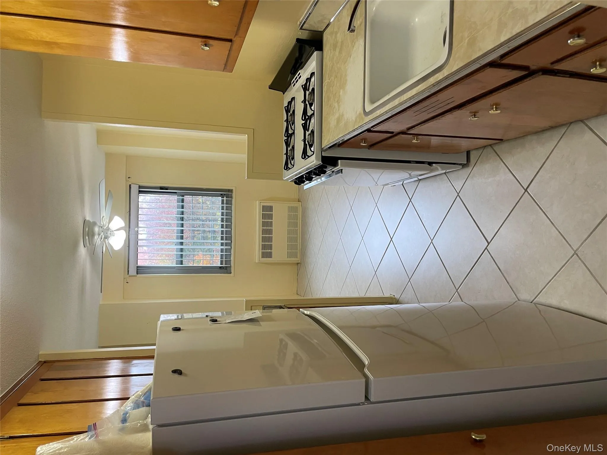 Kitchen featuring brown cabinets, fridge, range, and light tile patterned floors Kitchen featuring brown cabinets, fridge, range, and light tile patterned floors