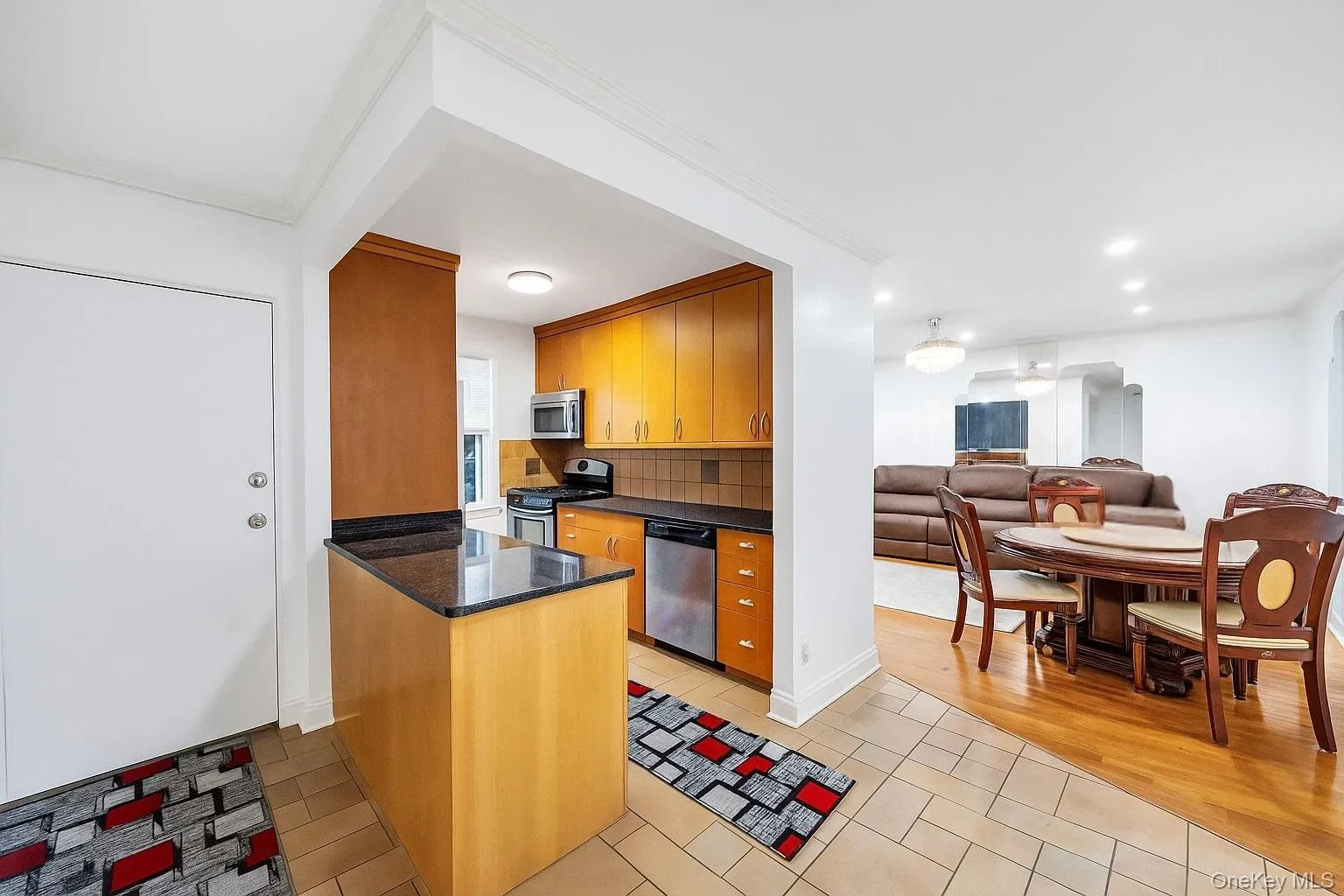 Kitchen featuring light tile patterned floors, appliances with stainless steel finishes, tasteful backsplash, open floor plan, and brown cabinets Kitchen featuring light tile patterned floors, appliances with stainless steel finishes, tasteful backsplash, open floor plan, and brown cabinets