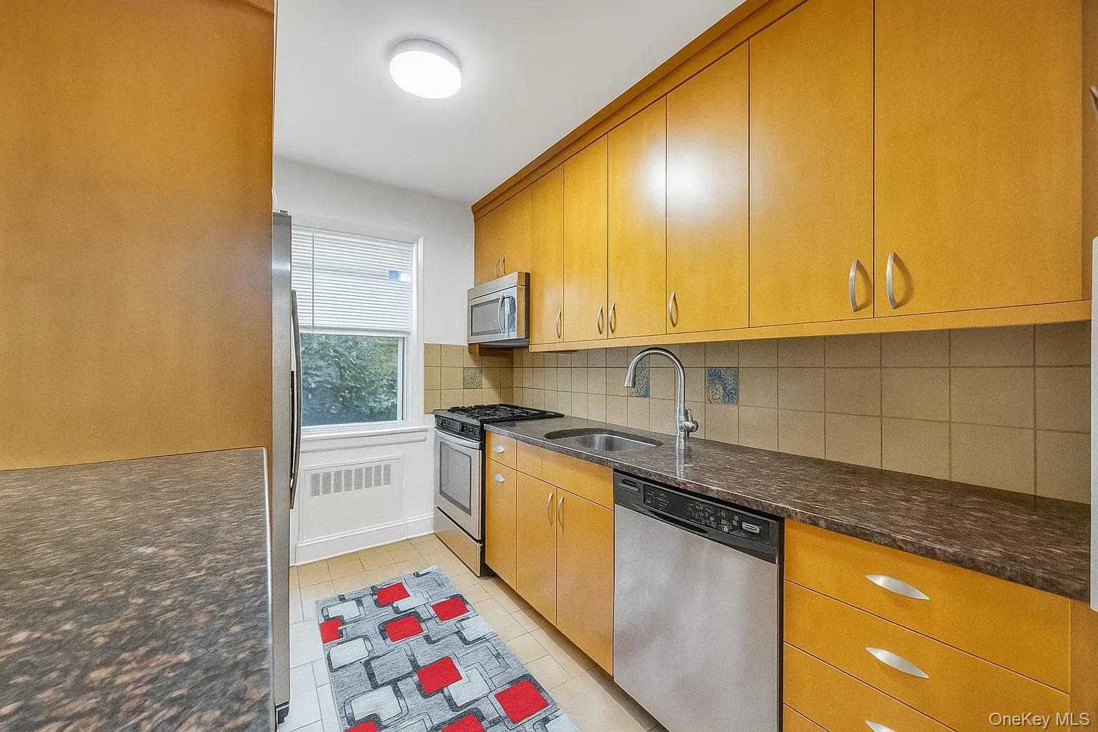 Kitchen with tasteful backsplash, appliances with stainless steel finishes, light tile patterned floors, and dark stone countertops Kitchen with tasteful backsplash, appliances with stainless steel finishes, light tile patterned floors, and dark stone countertops