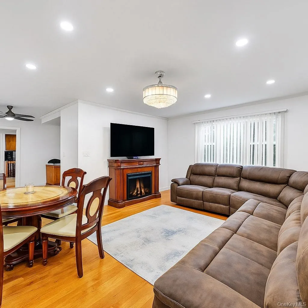 Living room featuring light wood-style flooring, a warm lit fireplace, recessed lighting, and a ceiling fan Living room featuring light wood-style flooring, a warm lit fireplace, recessed lighting, and a ceiling fan