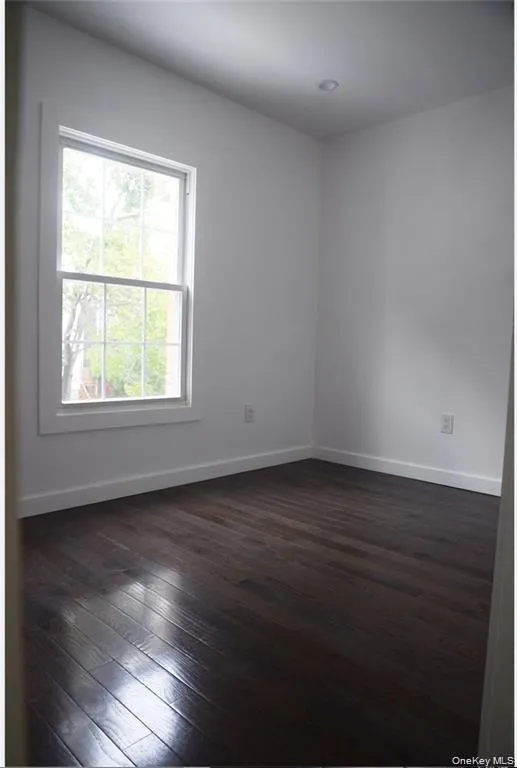 Spare room featuring dark wood-type flooring and baseboards Spare room featuring dark wood-type flooring and baseboards