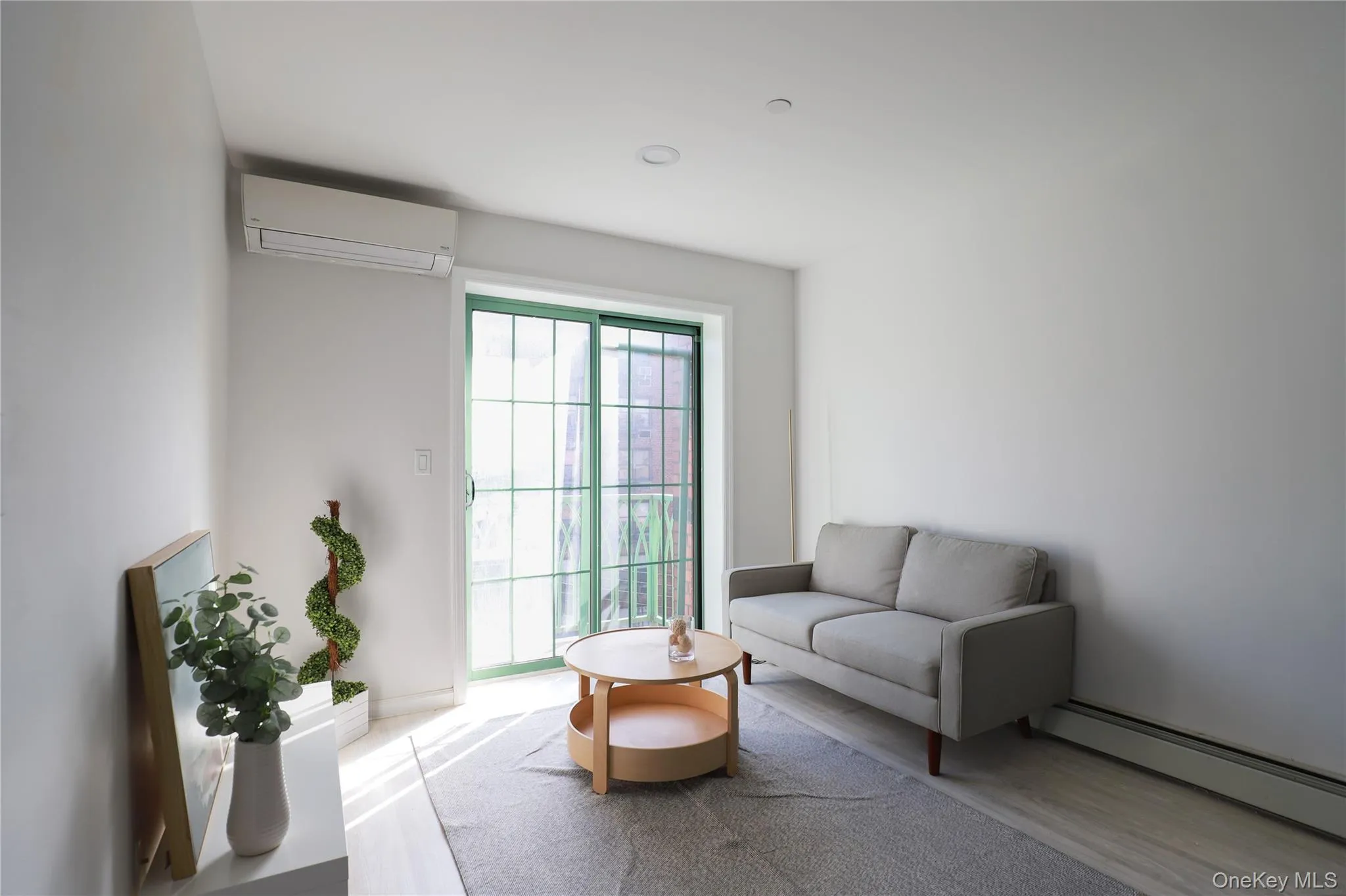 Living room with a baseboard heating unit, wood finished floors, and a wall mounted air conditioner Living room with a baseboard heating unit, wood finished floors, and a wall mounted air conditioner