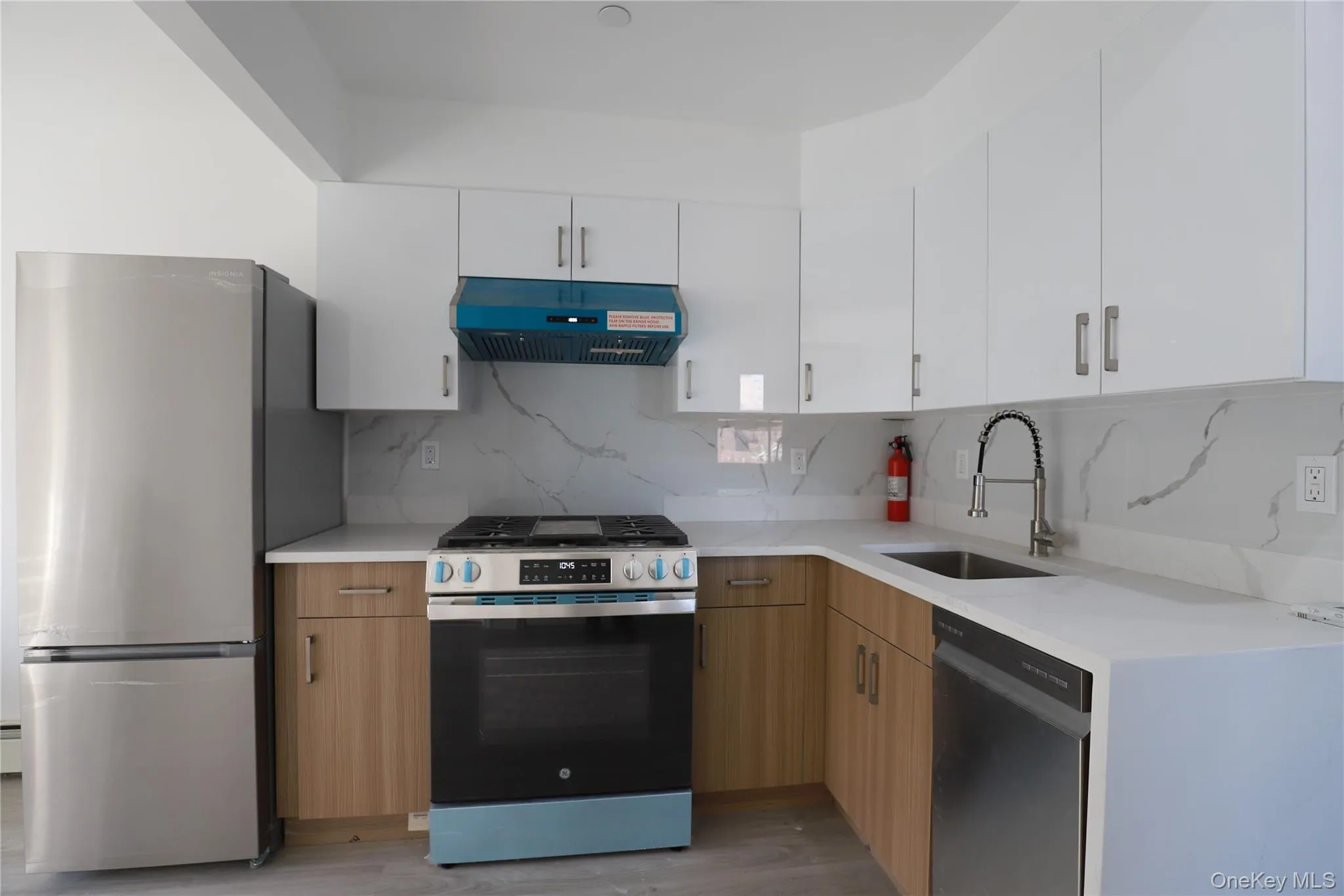 Kitchen featuring stainless steel appliances, tasteful backsplash, under cabinet range hood, and white cabinetry Kitchen featuring stainless steel appliances, tasteful backsplash, under cabinet range hood, and white cabinetry