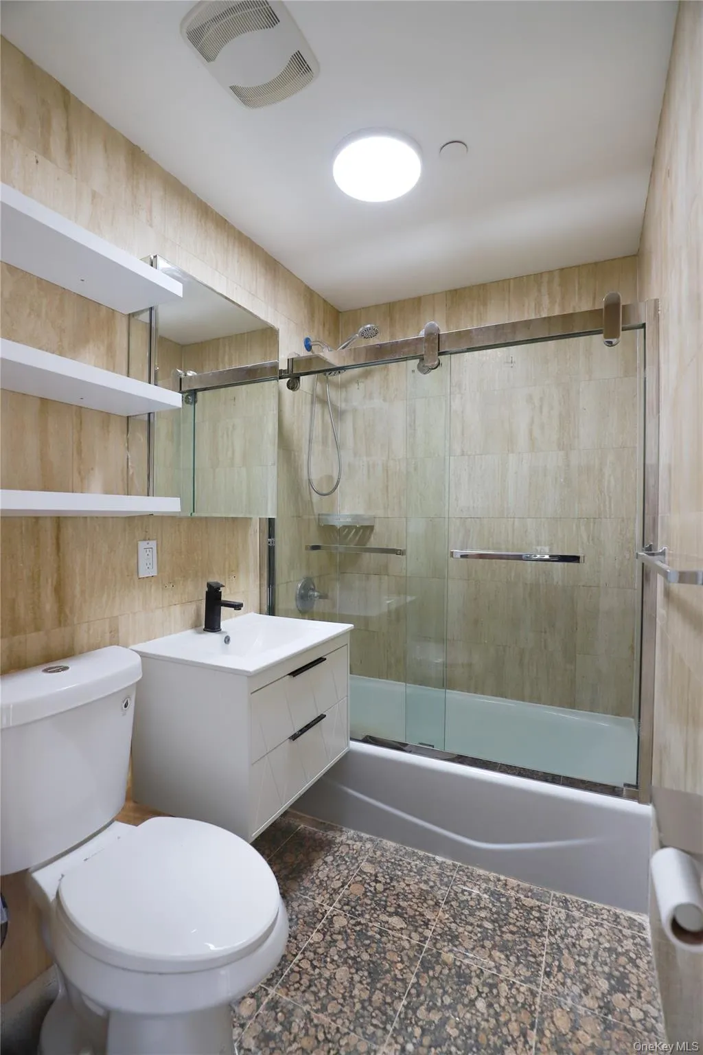 Bathroom featuring vanity, combined bath / shower with glass door, and tile walls Bathroom featuring vanity, combined bath / shower with glass door, and tile walls
