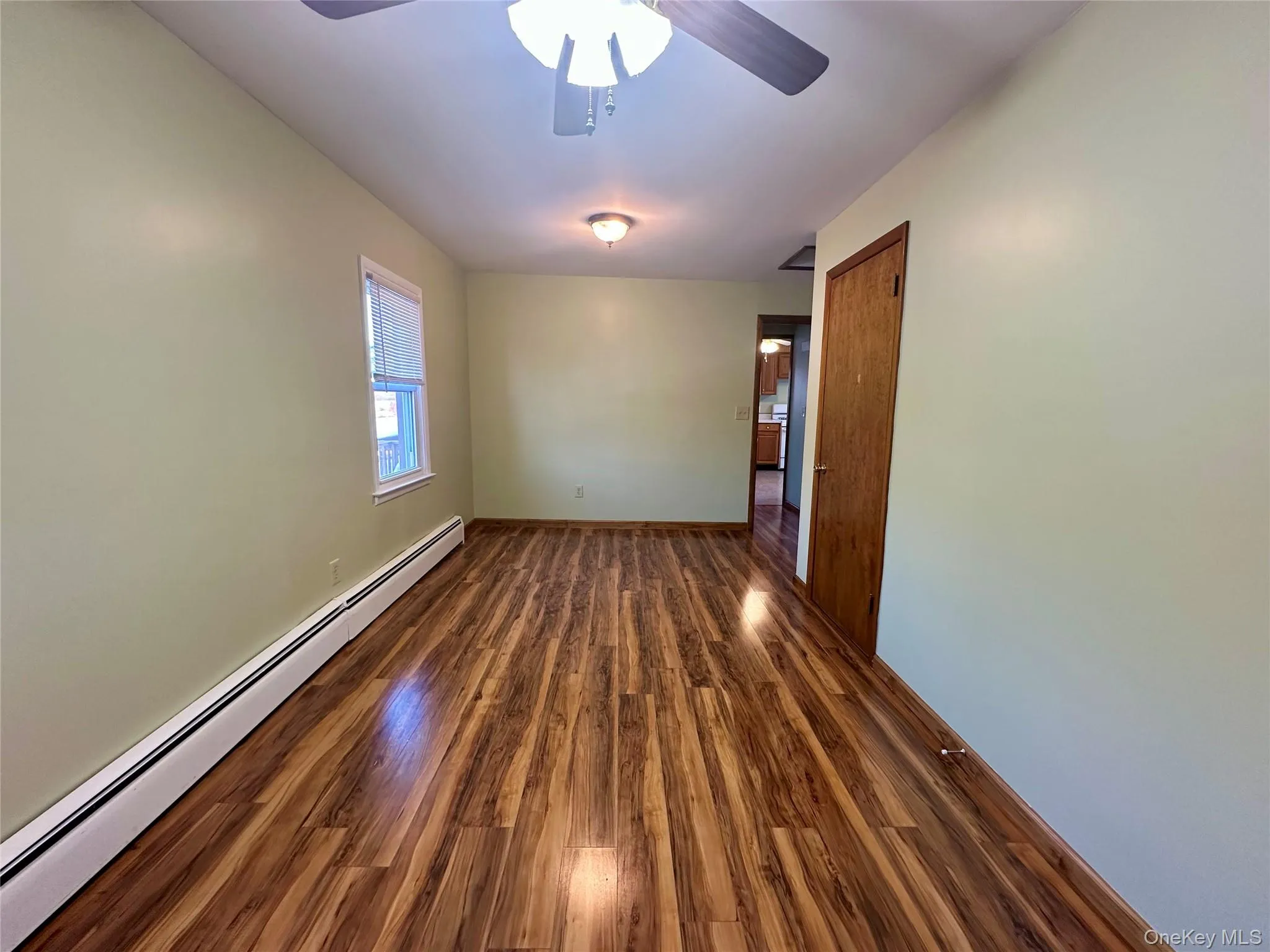 Spare room featuring a baseboard heating unit, dark wood-style floors, and a ceiling fan Spare room featuring a baseboard heating unit, dark wood-style floors, and a ceiling fan