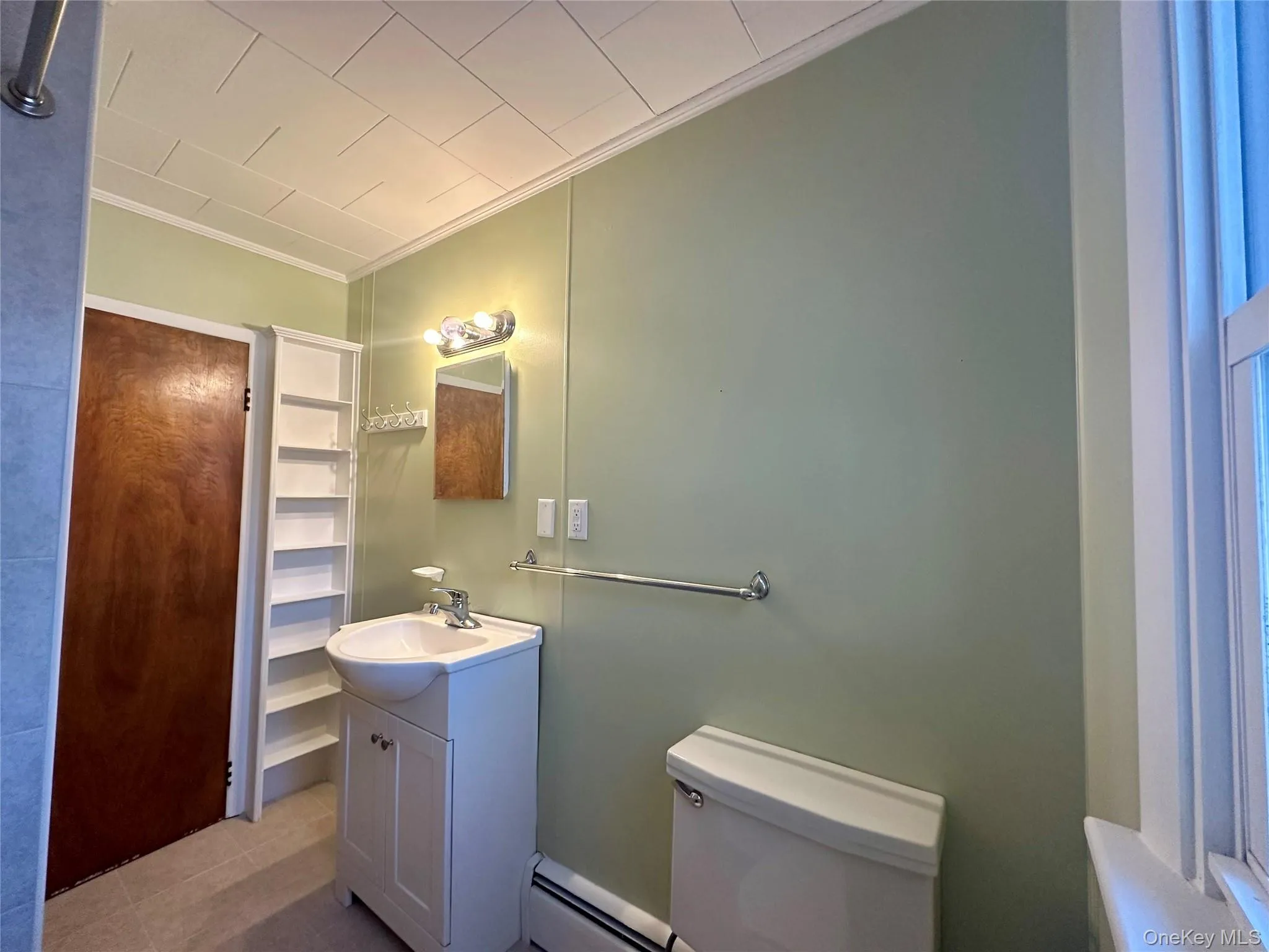 Bathroom featuring crown molding, baseboard heating, vanity, and tile patterned flooring Bathroom featuring crown molding, baseboard heating, vanity, and tile patterned flooring