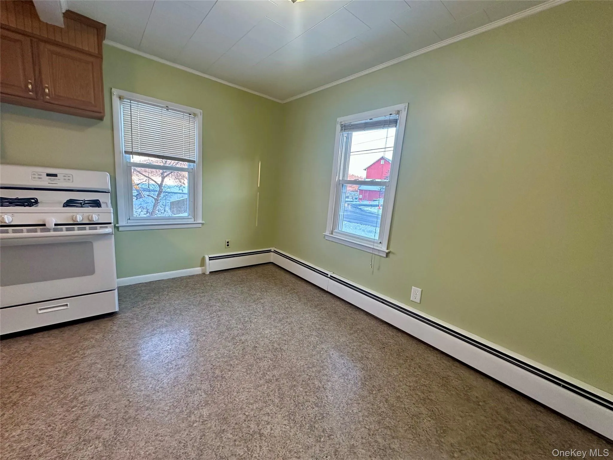 Kitchen with white gas range oven, a baseboard heating unit, and ornamental molding Kitchen with white gas range oven, a baseboard heating unit, and ornamental molding