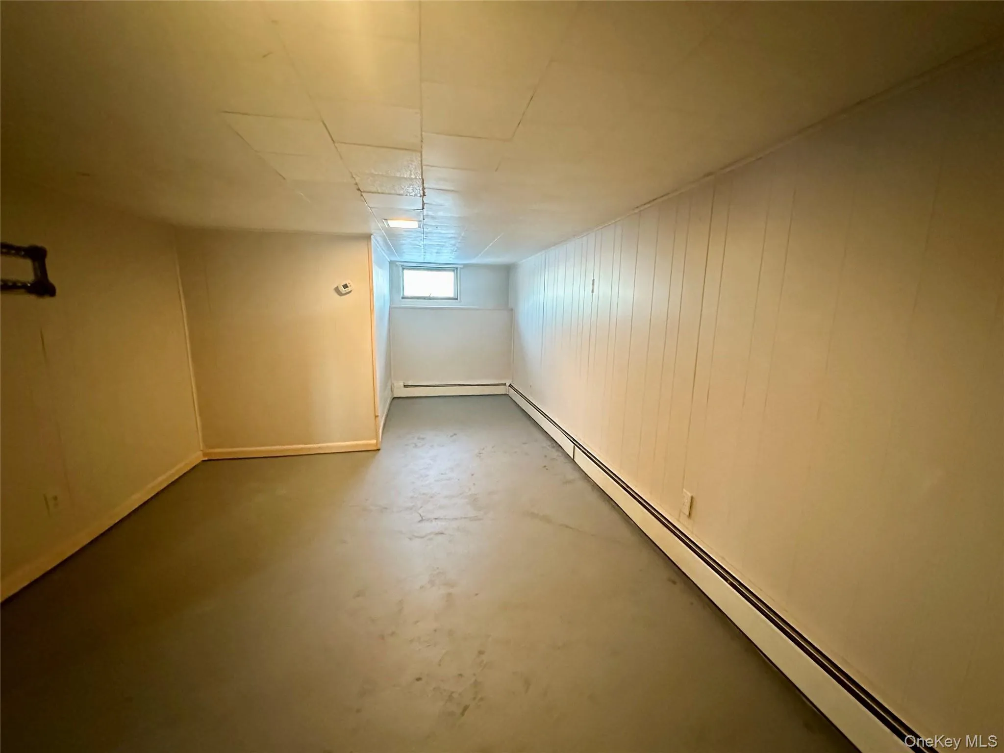 Below grade area featuring a baseboard radiator and wood walls Below grade area featuring a baseboard radiator and wood walls