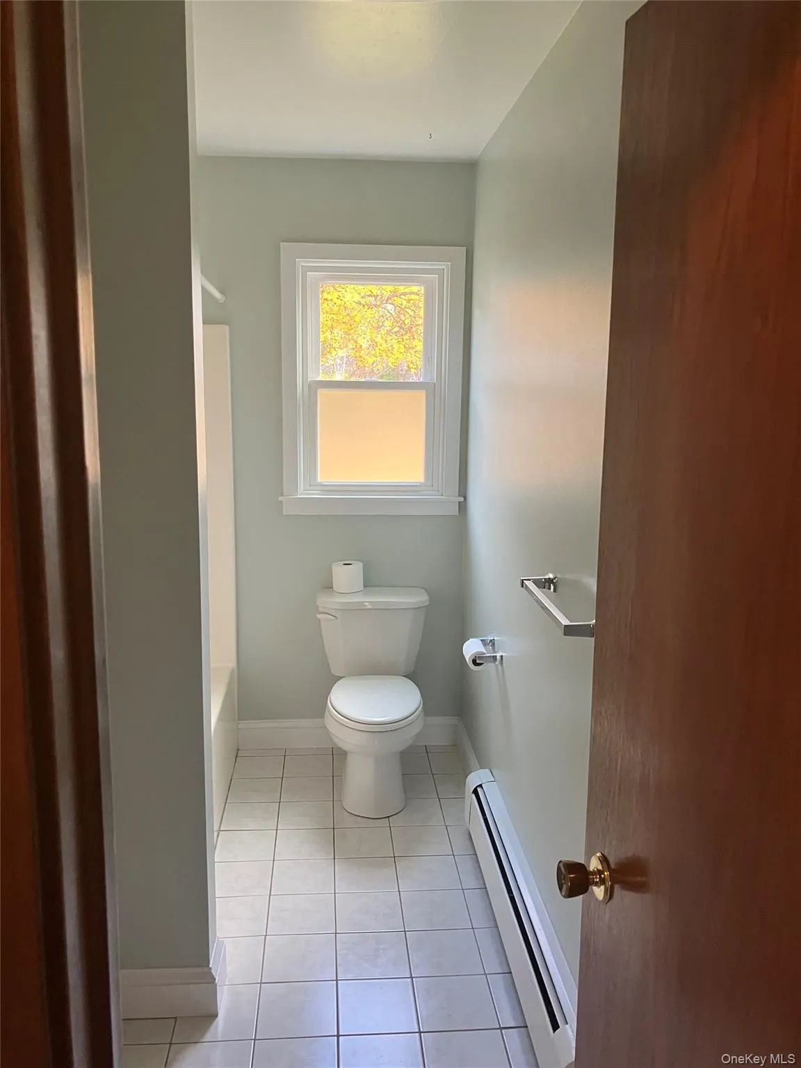 Bathroom with a baseboard heating unit, light tile patterned flooring, and shower / bath combination Bathroom with a baseboard heating unit, light tile patterned flooring, and shower / bath combination