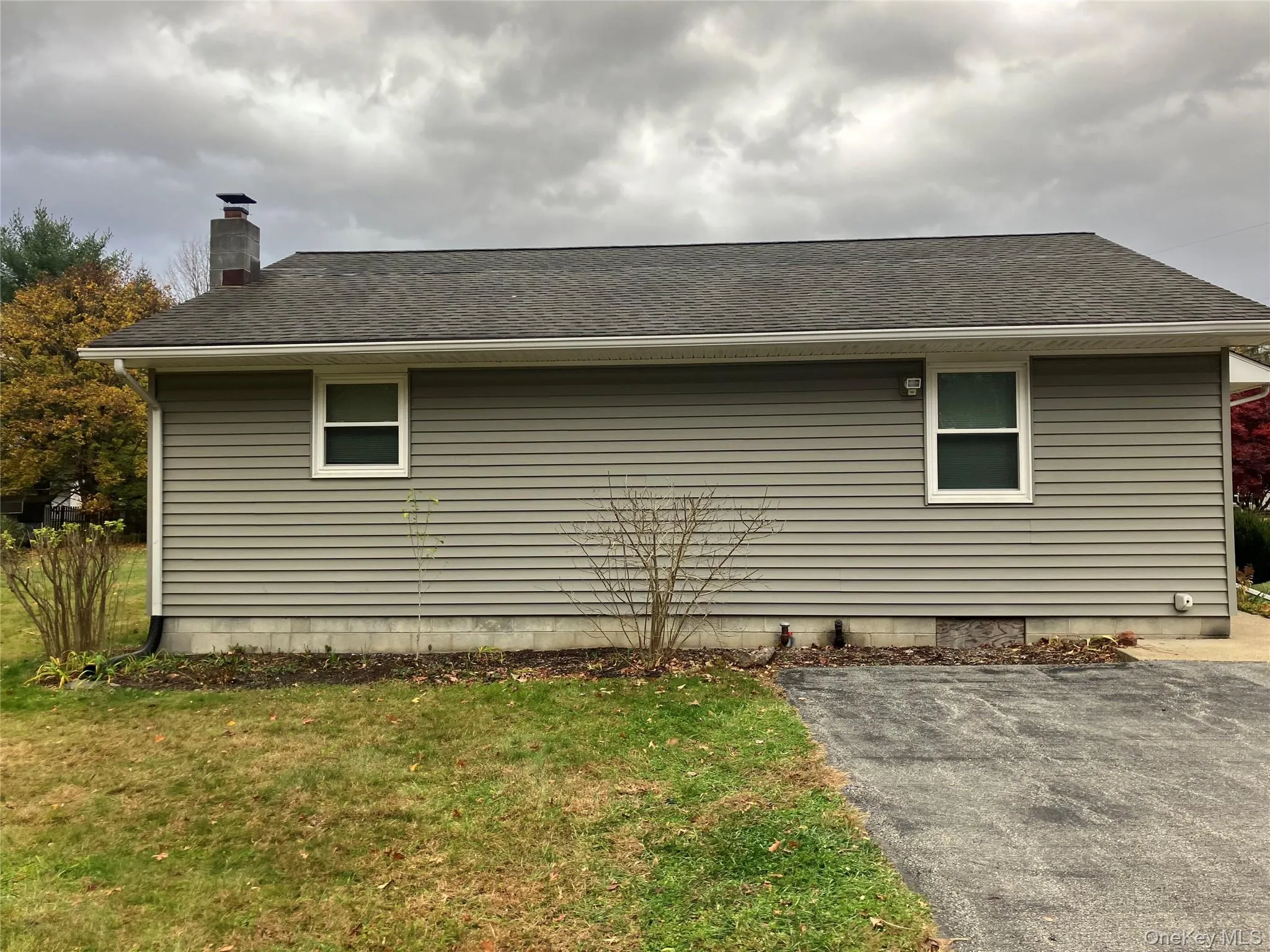 View of home's exterior with a lawn, a shingled roof, and a chimney View of home's exterior with a lawn, a shingled roof, and a chimney