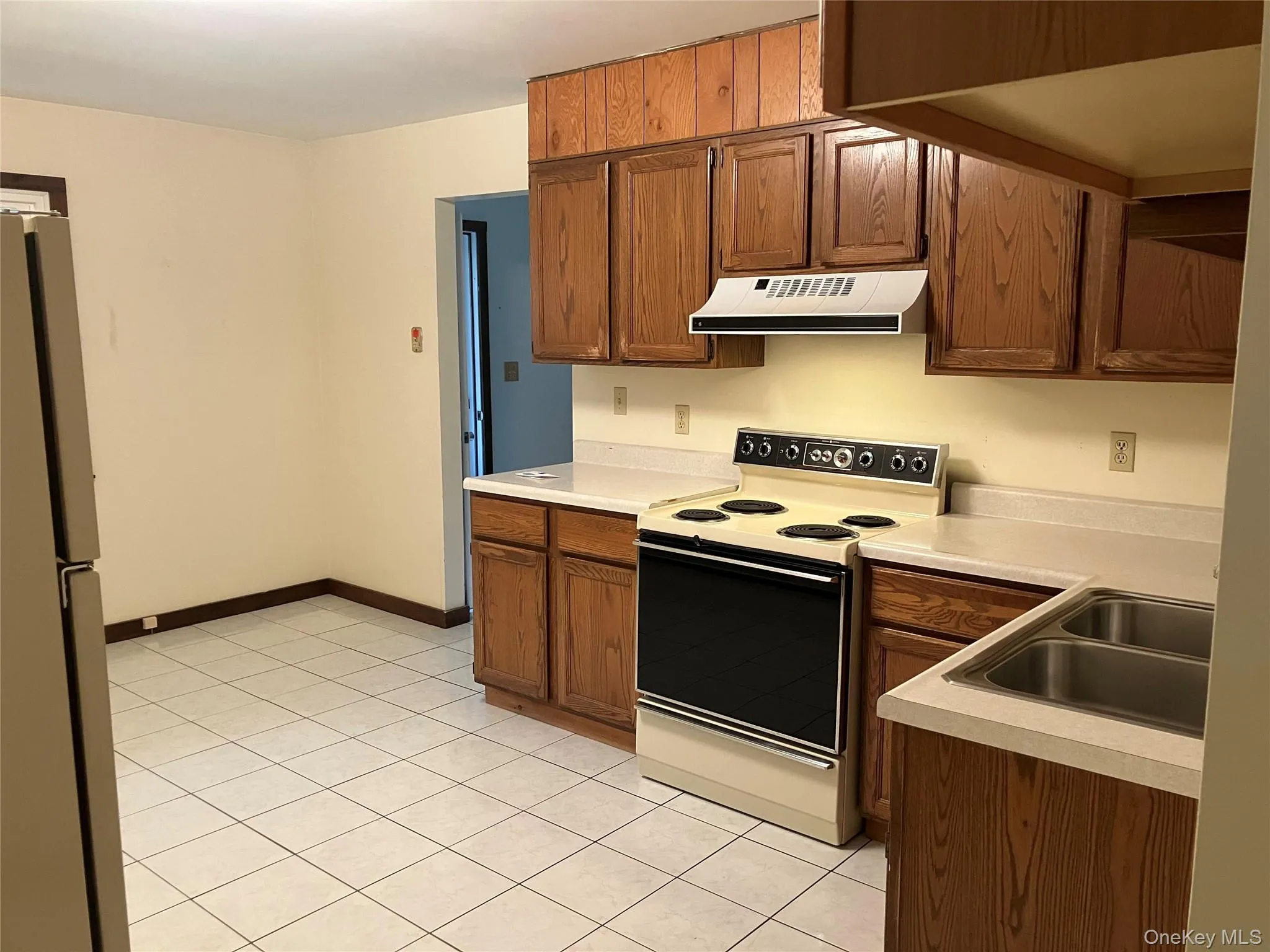 Kitchen with range with electric cooktop, freestanding refrigerator, light countertops, and range hood Kitchen with range with electric cooktop, freestanding refrigerator, light countertops, and range hood