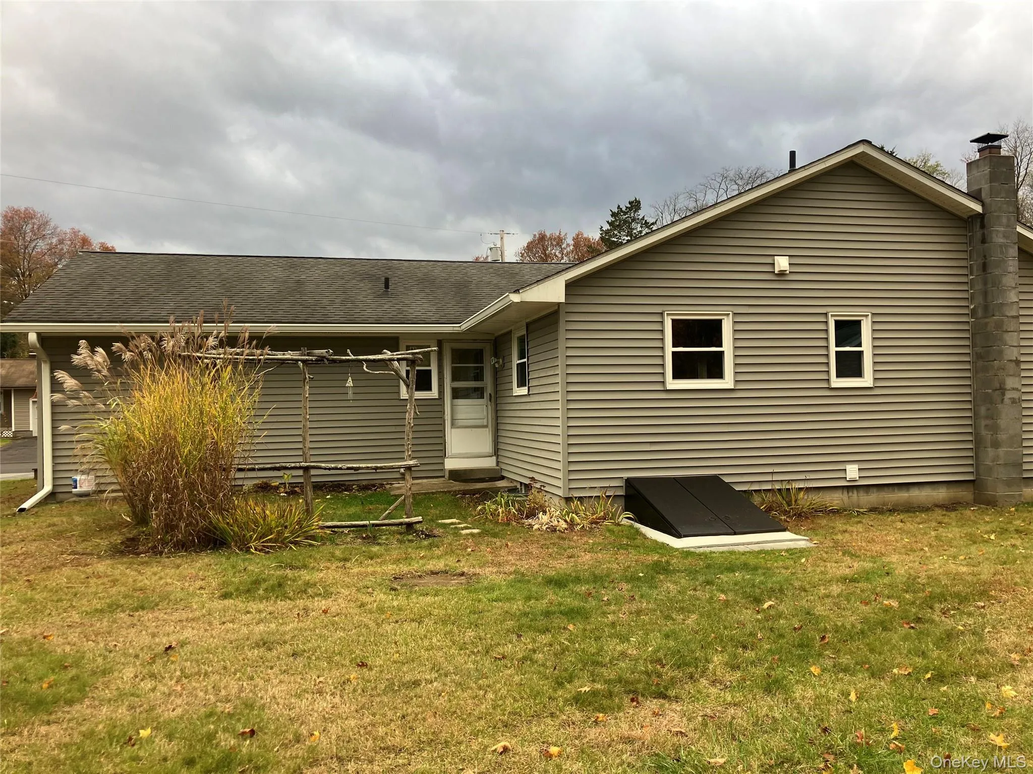 Back of house with a yard, a shingled roof, and a chimney Back of house with a yard, a shingled roof, and a chimney