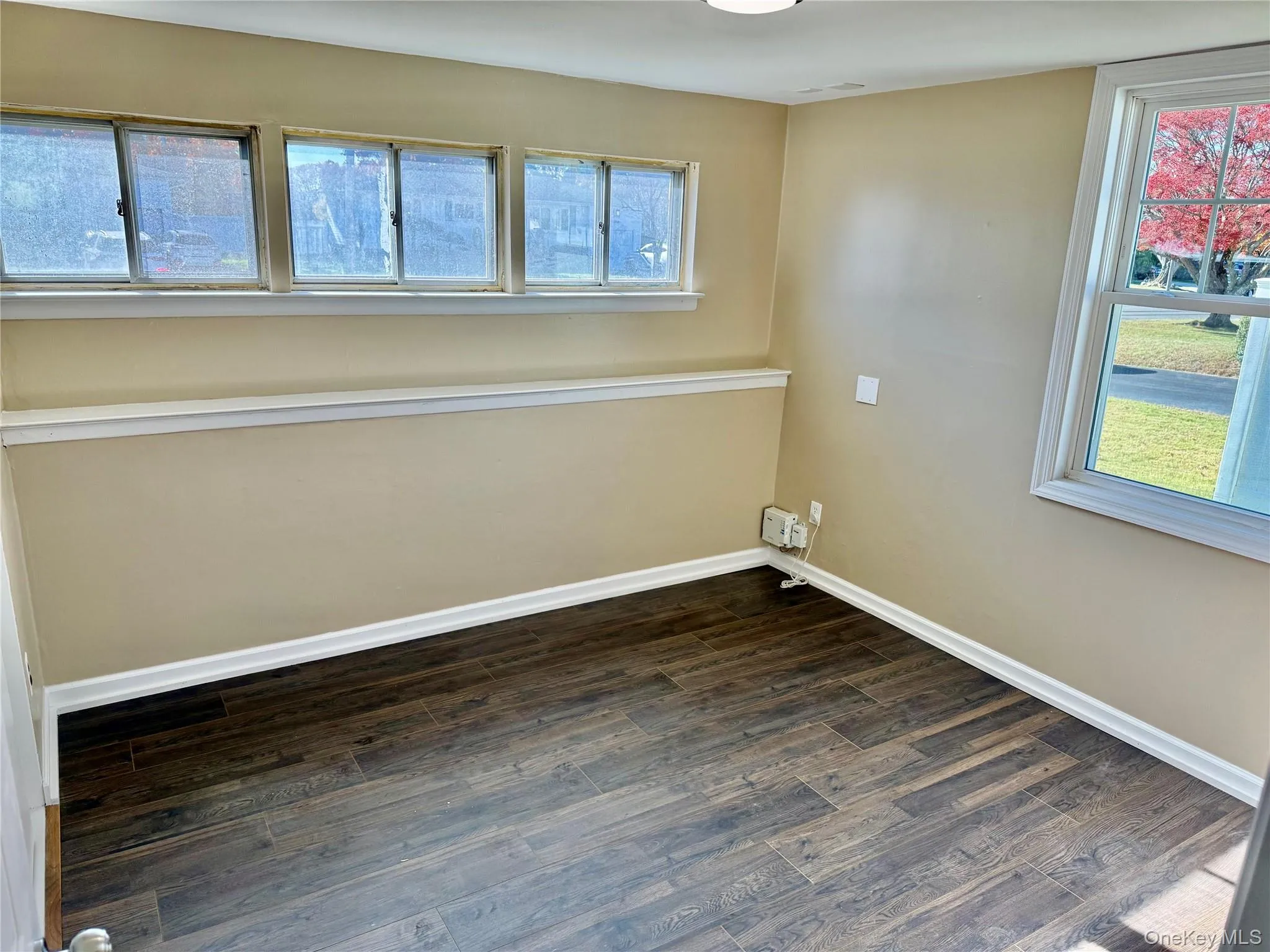 Unfurnished room featuring dark wood-style floors and baseboards Unfurnished room featuring dark wood-style floors and baseboards
