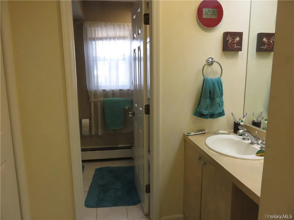 Full bathroom featuring vanity, a baseboard heating unit, and light tile patterned floors Full bathroom featuring vanity, a baseboard heating unit, and light tile patterned floors