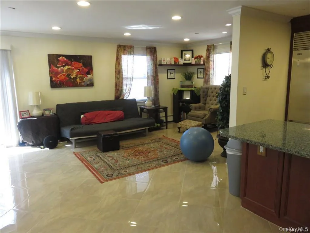 Living room with plenty of natural light, recessed lighting, ornamental molding, and a baseboard heating unit Living room with plenty of natural light, recessed lighting, ornamental molding, and a baseboard heating unit