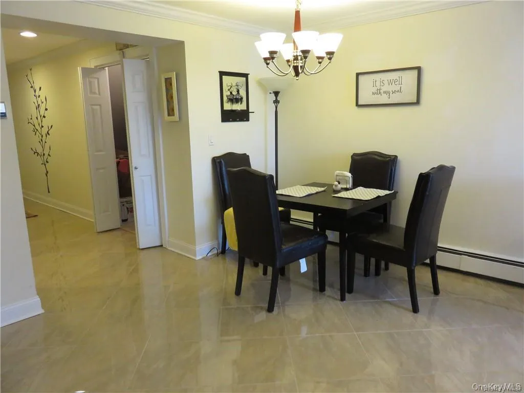 Dining space featuring a baseboard radiator, ornamental molding, a chandelier, and light tile patterned flooring Dining space featuring a baseboard radiator, ornamental molding, a chandelier, and light tile patterned flooring