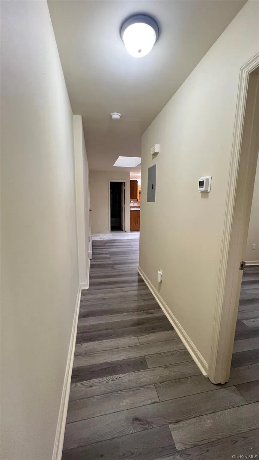 Hallway with dark wood-style floors and baseboards Hallway with dark wood-style floors and baseboards