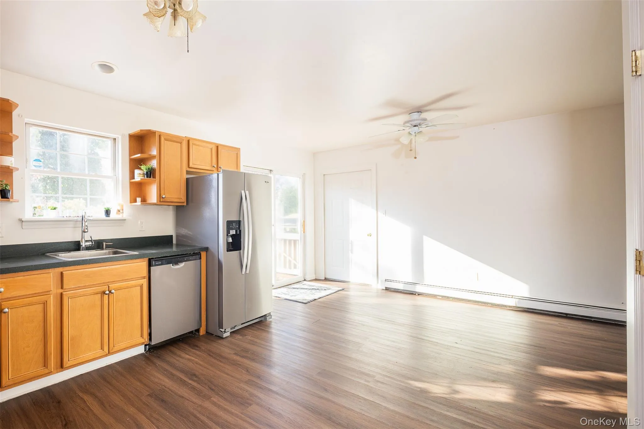 Kitchen featuring dark countertops, a ceiling fan, dark wood-type flooring, appliances with stainless steel finishes, and brown cabinets Kitchen featuring dark countertops, a ceiling fan, dark wood-type flooring, appliances with stainless steel finishes, and brown cabinets