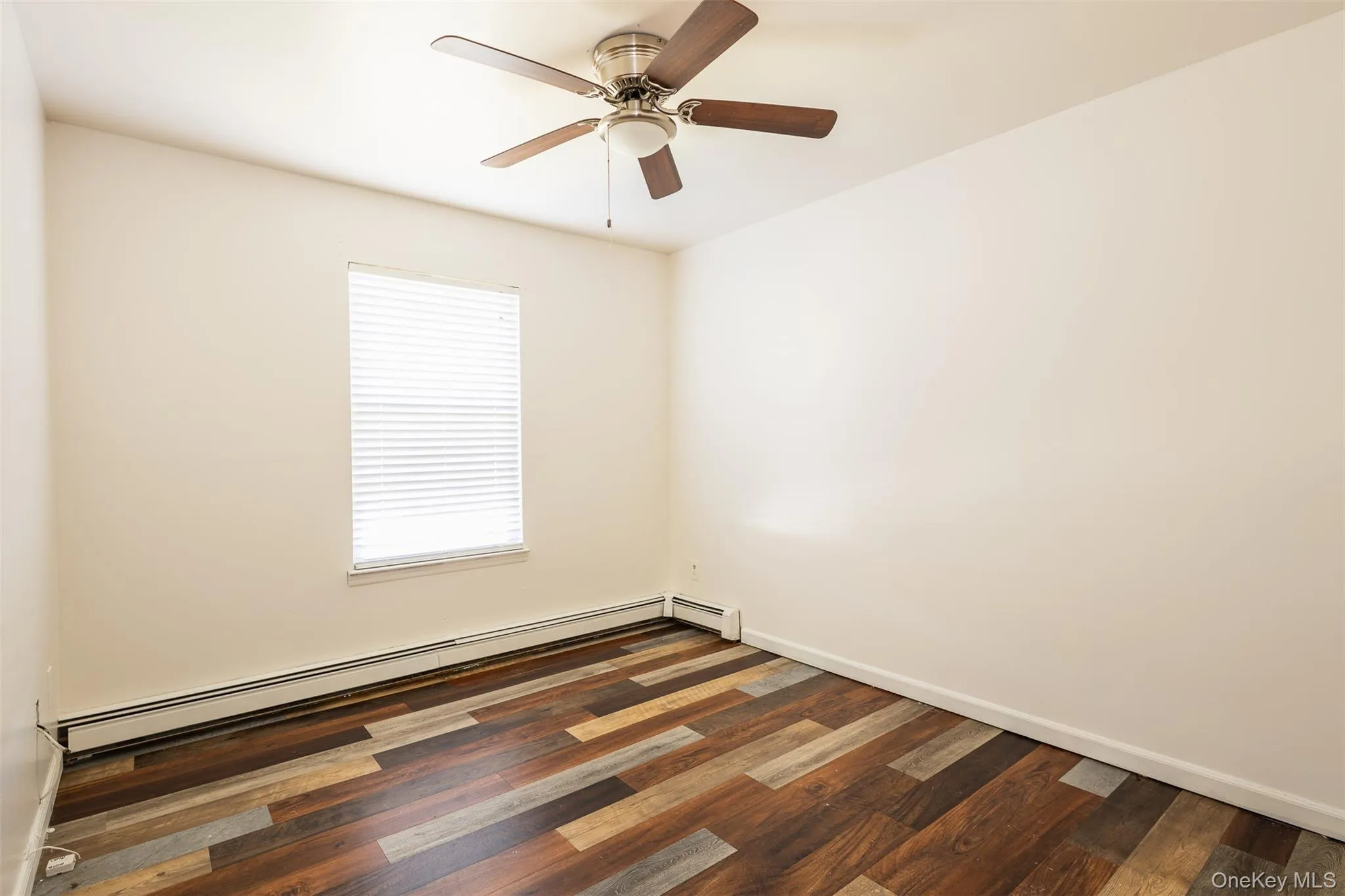 Unfurnished room featuring a baseboard heating unit, dark wood finished floors, and ceiling fan Unfurnished room featuring a baseboard heating unit, dark wood finished floors, and ceiling fan